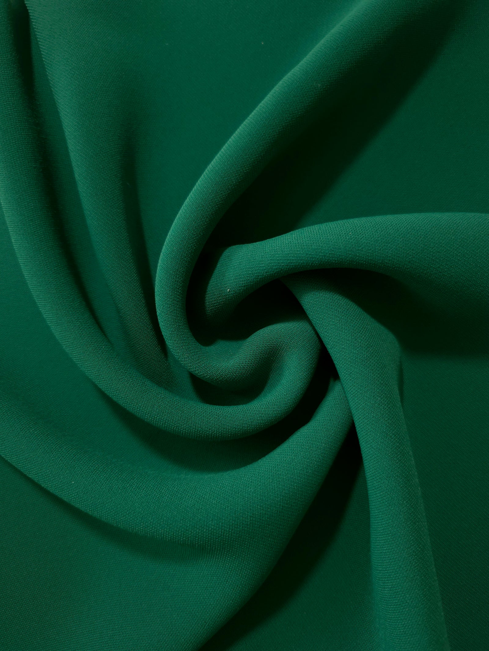 Spiral styling of Forest Green Korean polyester crepe showing supple drape for abayas, dresses and occasionwear