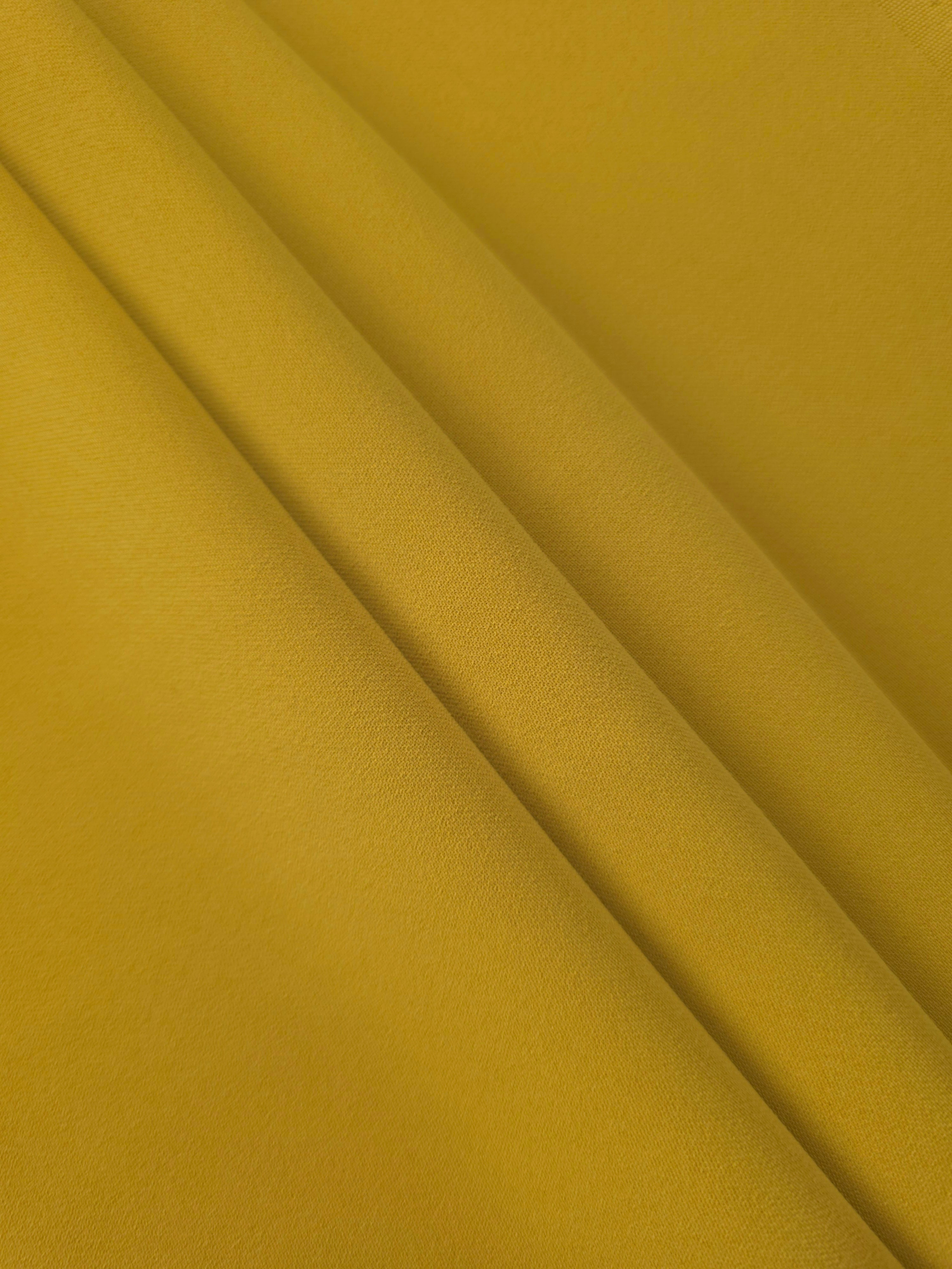 Layered Golden Ochre Korean polyester crepe showing gentle mechanical stretch and soft structure for dressmaking