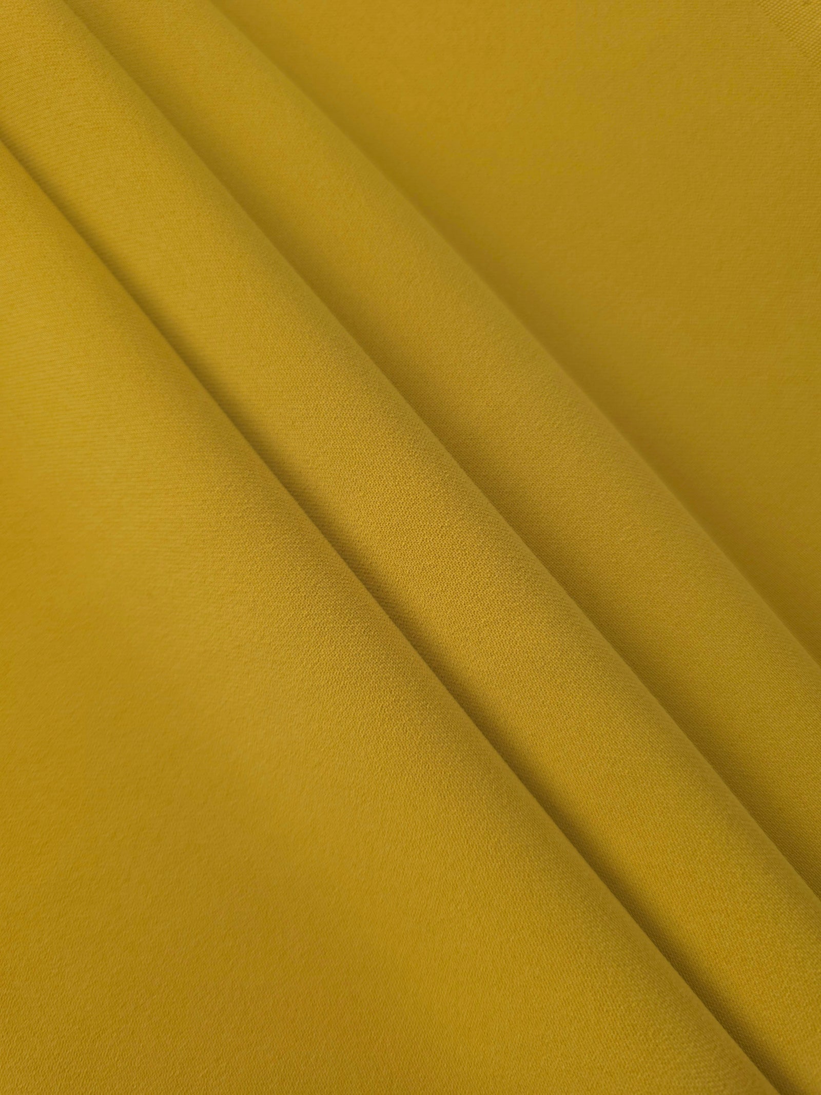 Layered Golden Ochre Korean polyester crepe showing gentle mechanical stretch and soft structure for dressmaking