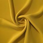 Golden Ochre silky-soft polyester crepe styled in a swirl to show fluid dressmaking drape and movement