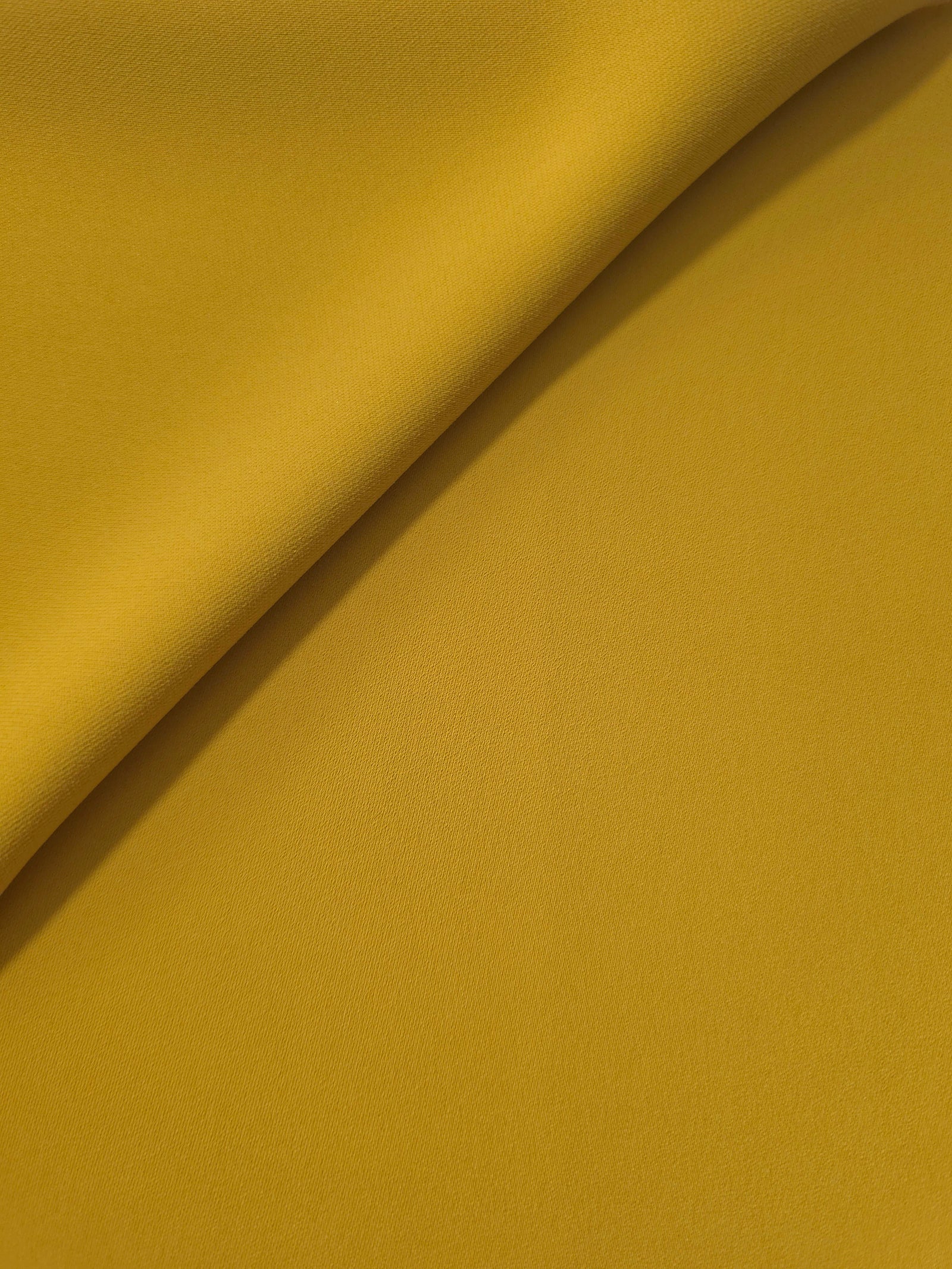 Golden Ochre opaque Korean polyester crepe in a soft fold, showing flowing drape for garment making