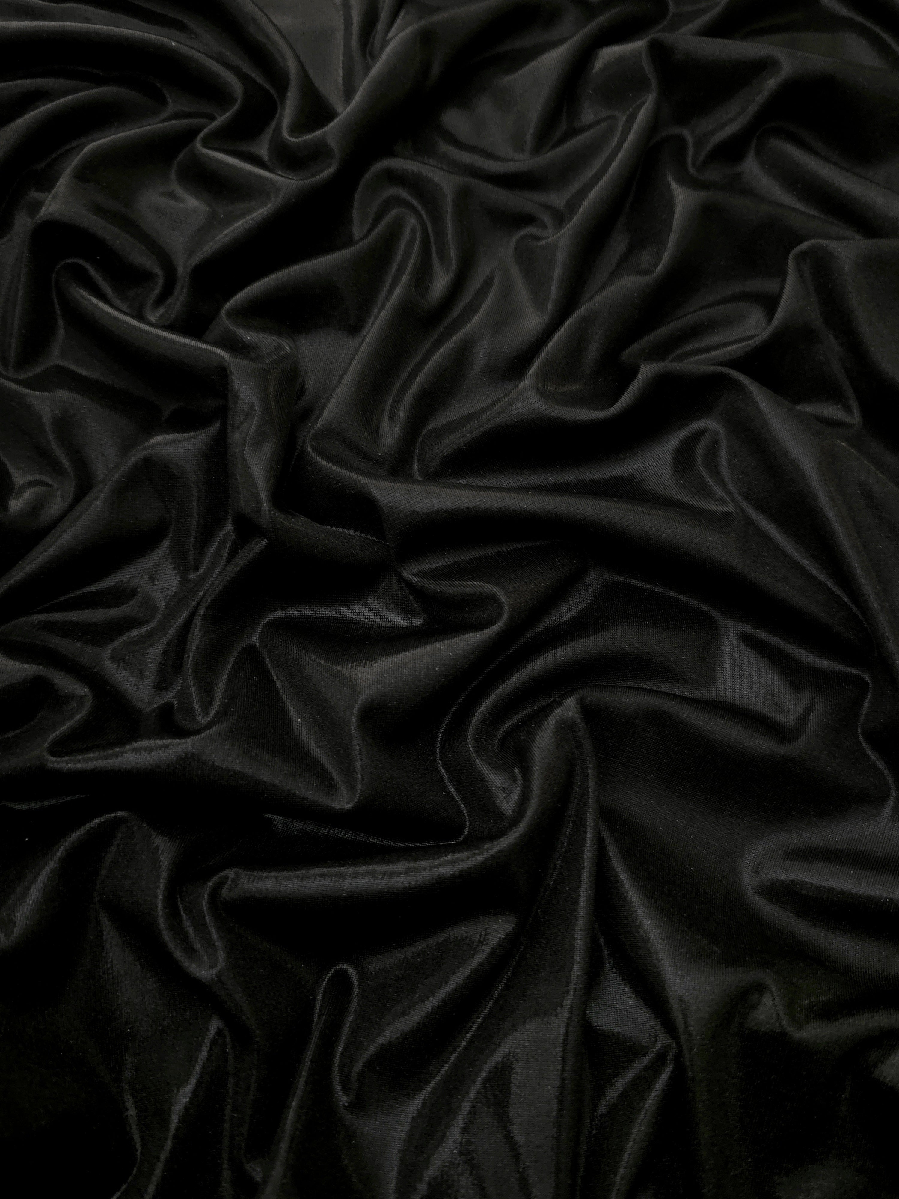 Jet Black shimmer stretch fabric in draped folds, highlighting metallic foil sheen for evening dresses, costumes and statement apparel