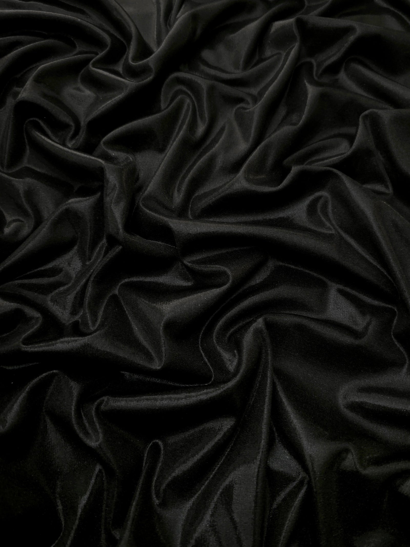 Jet Black shimmer stretch fabric in draped folds, highlighting metallic foil sheen for evening dresses, costumes and statement apparel