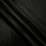 Jet Black metallic foiled spandex in layered folds, highlighting reflective texture and flexible structure for stage and eveningwear