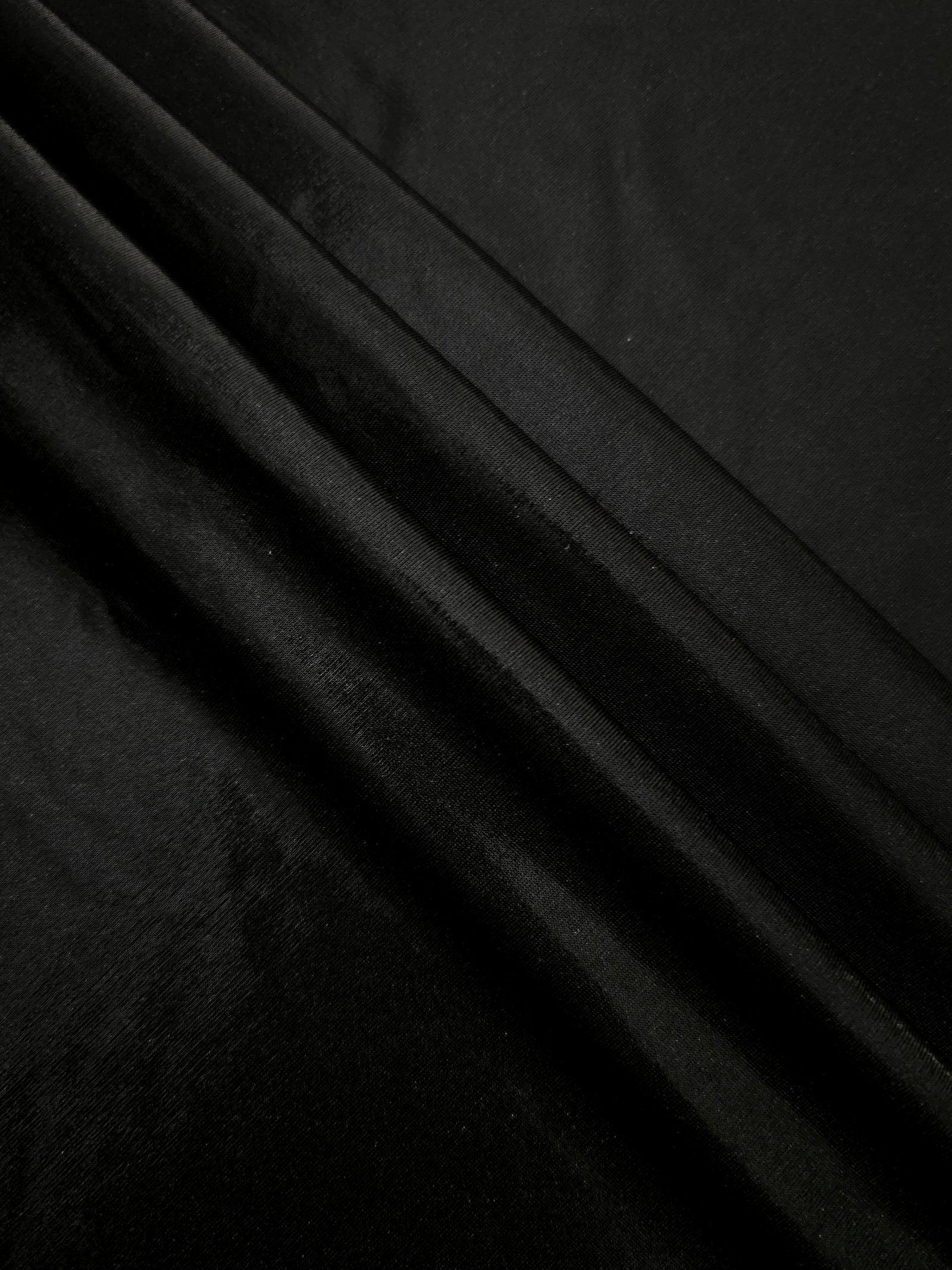 Jet Black metallic foiled spandex in layered folds, highlighting reflective texture and flexible structure for stage and eveningwear