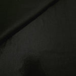 Soft fold of Jet Black metallic foiled spandex highlighting reflective sheen and supple movement for dresses and stagewear