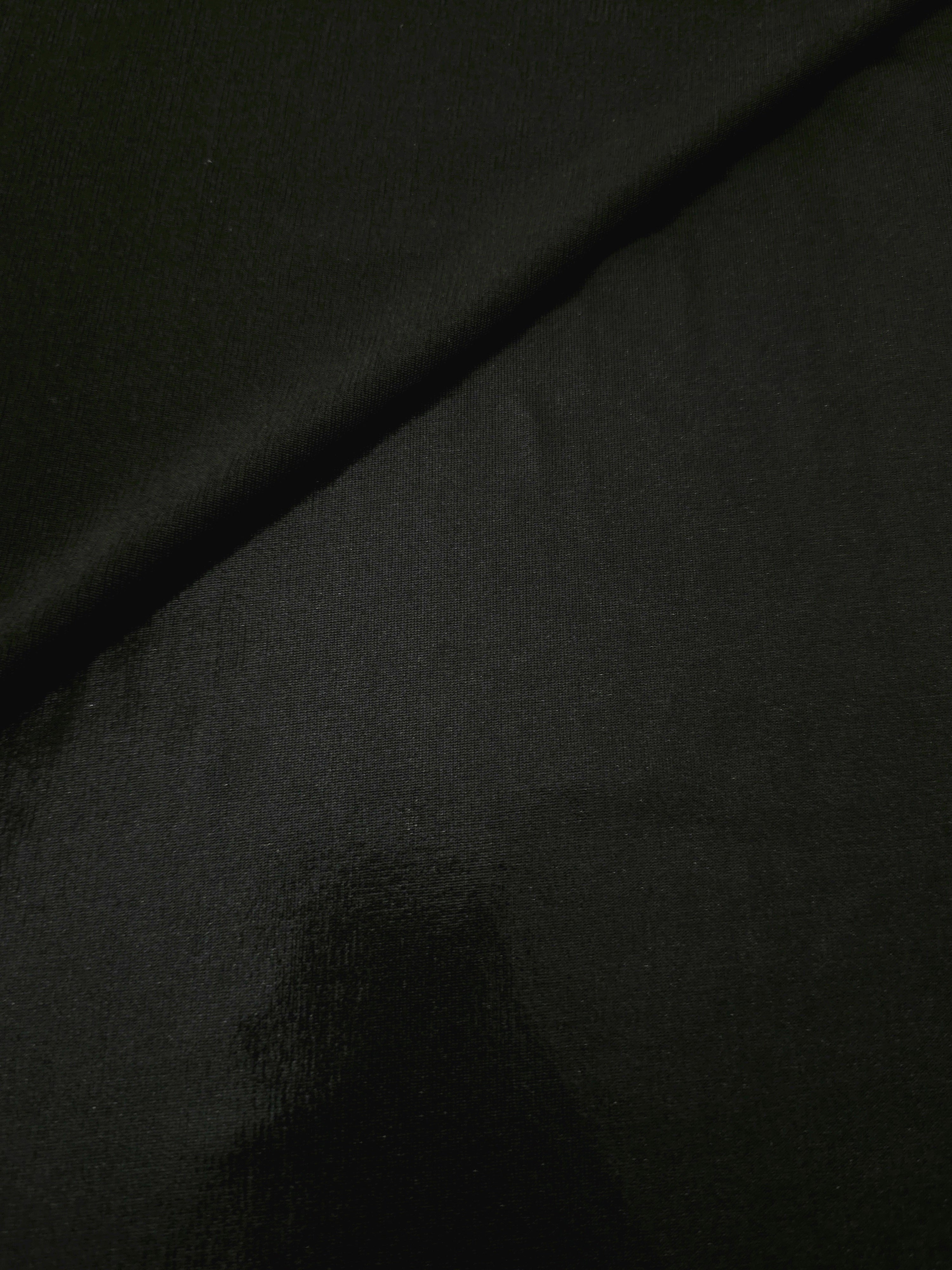 Soft fold of Jet Black metallic foiled spandex highlighting reflective sheen and supple movement for dresses and stagewear