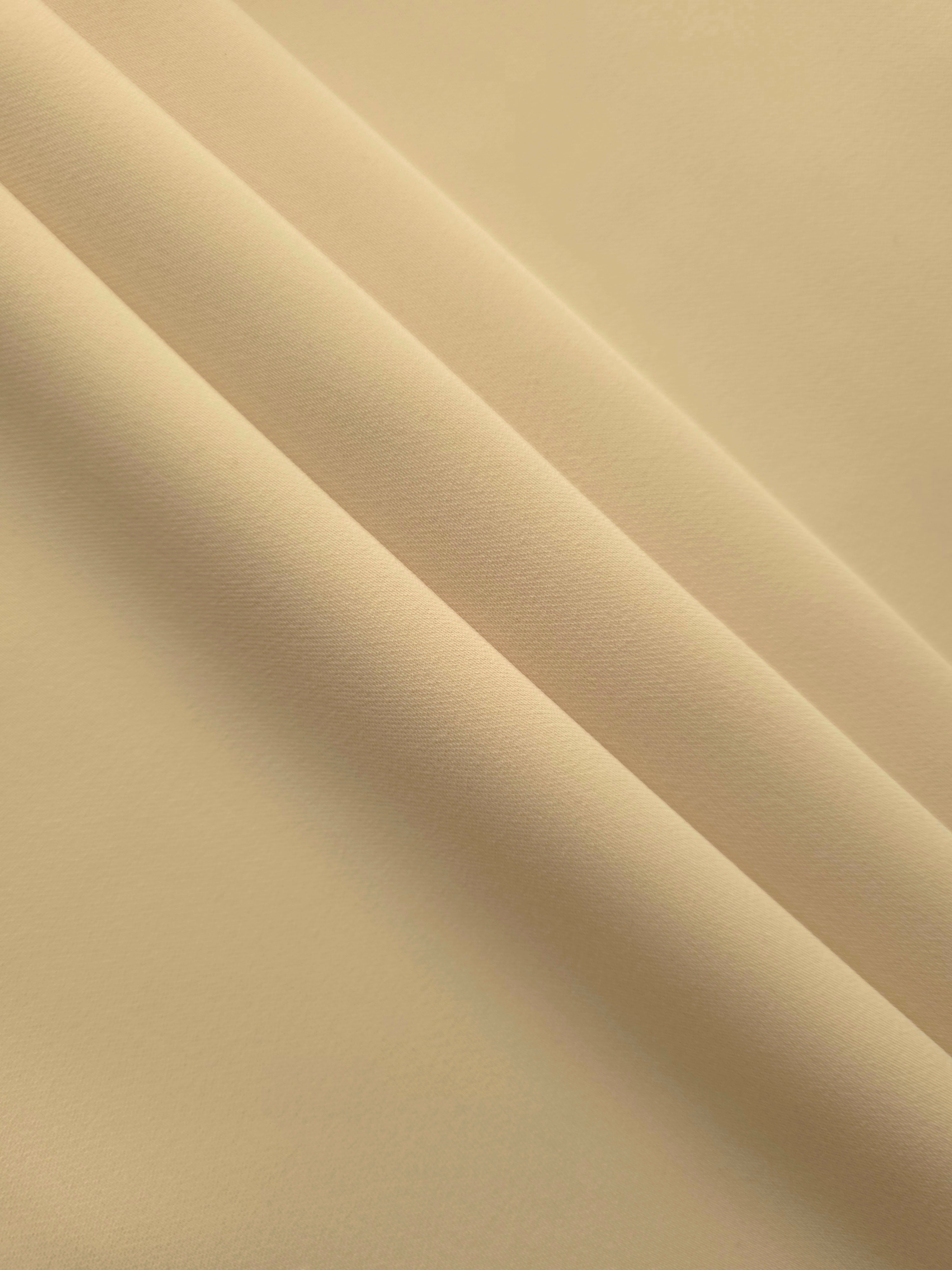 Khaki Beige mechanical polyester crepe in layered folds, showing soft body and gentle stretch for separates