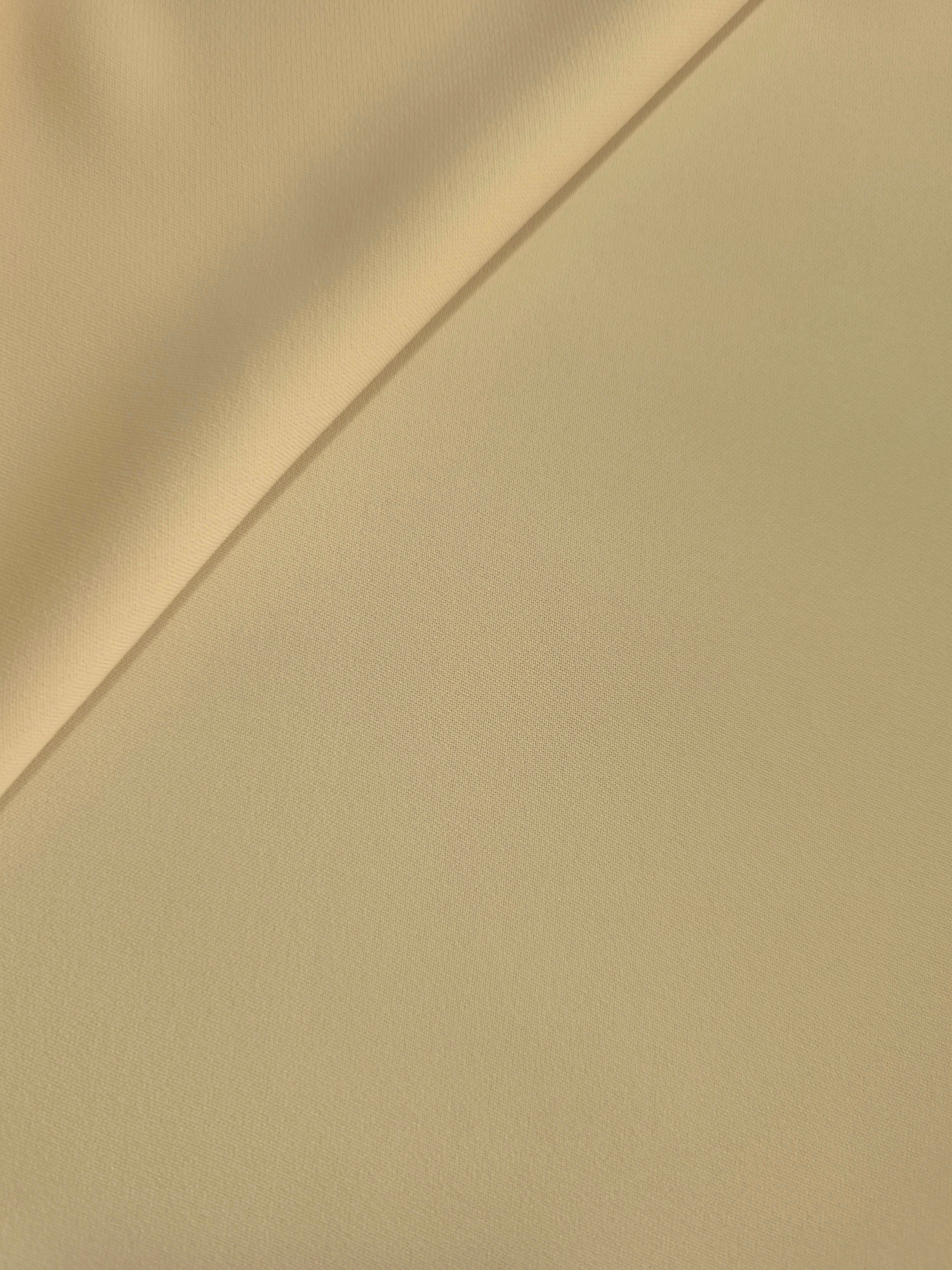 Soft fold of Khaki Beige polyester crepe showing fluid dressmaking drape for dresses, skirts and blouses