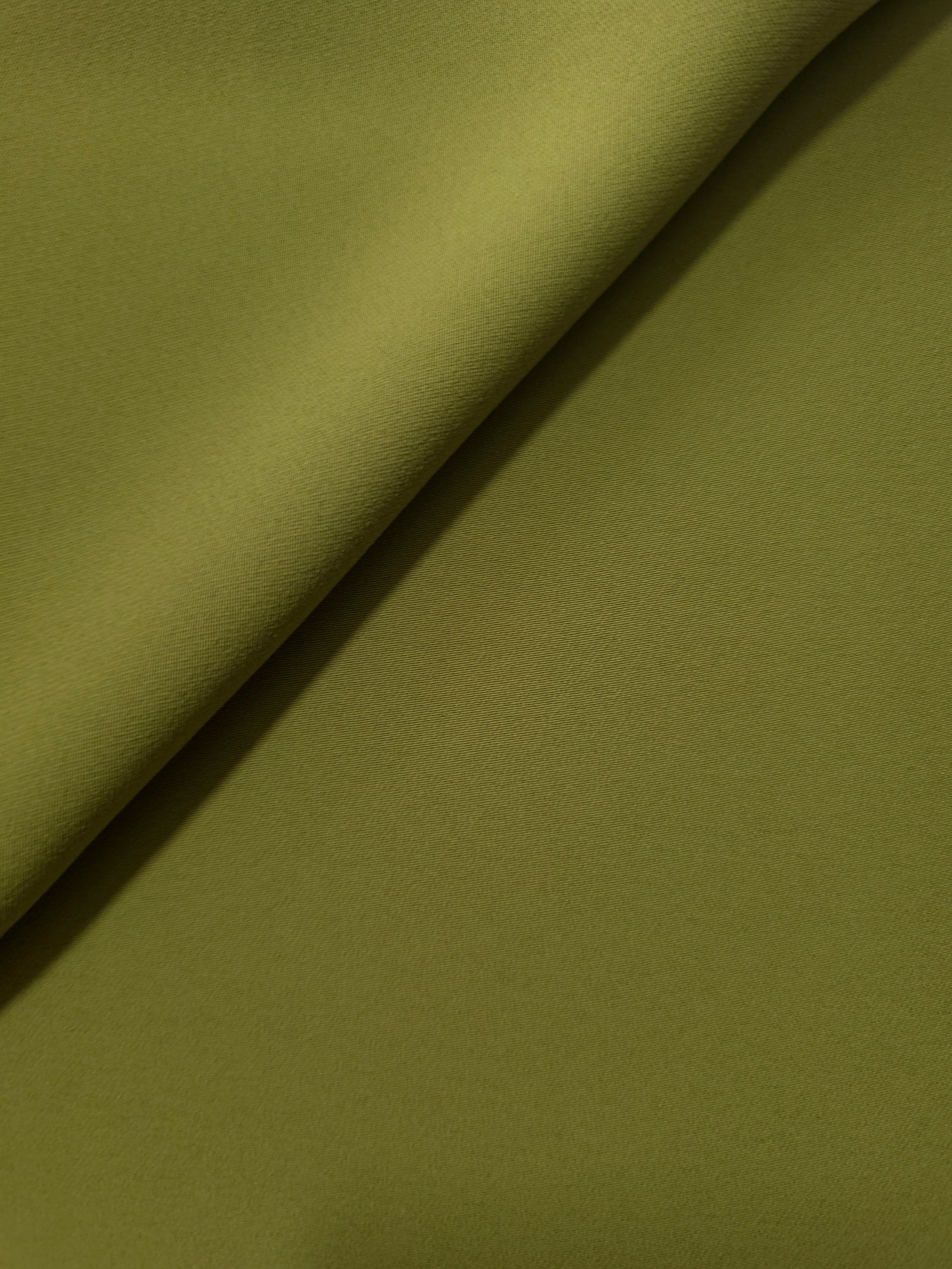 Soft fold of Khaki Olive Green opaque polyester crepe showing fluid dressmaking drape for dresses and skirts