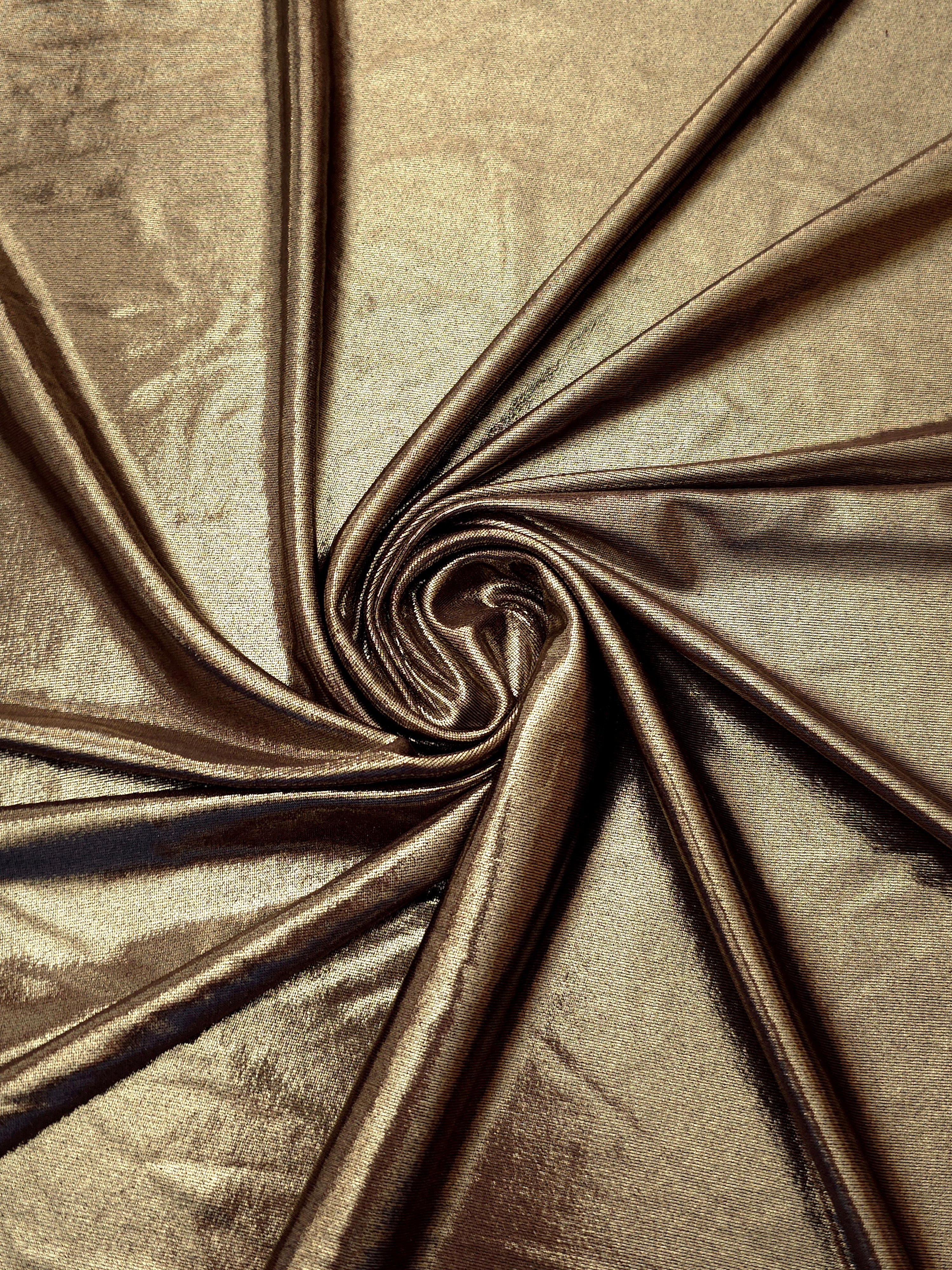 Khaki Taupe metallic stretch fabric in a flowing swirl, emphasizing foil shimmer and drape for partywear and statement fashion