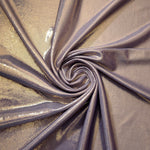 Lavender Taupe metallic stretch fabric in a flowing swirl, emphasizing foil shimmer and drape for partywear and statement fashion