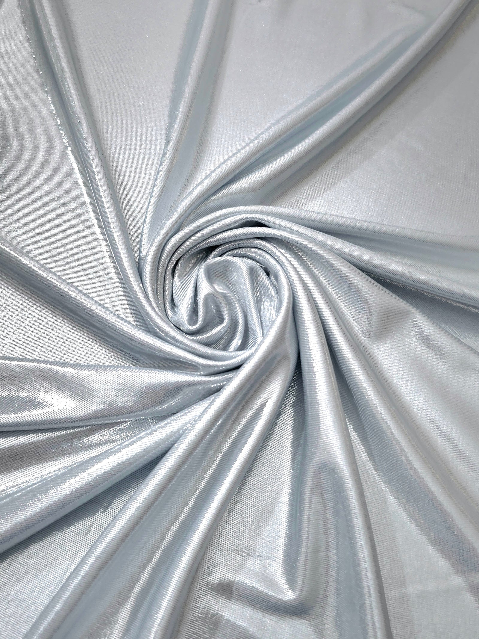 Flowing swirl of Light Silver Gray metallic stretch fabric, showing dynamic foil reflection for stagewear, skirts and creative fashion