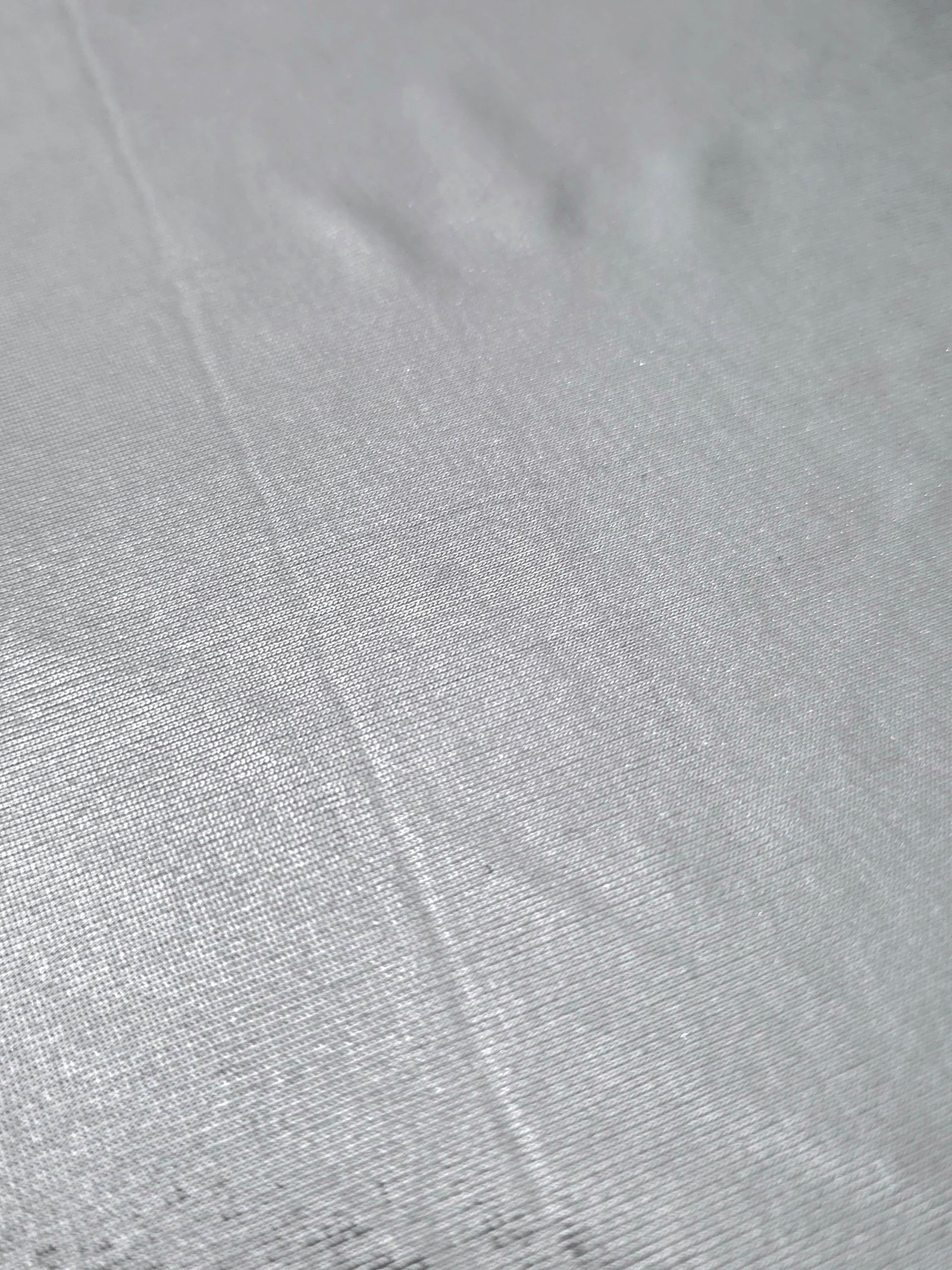 Light Silver Gray foiled stretch fabric texture close-up, displaying metallic reflection and fine surface character for apparel design