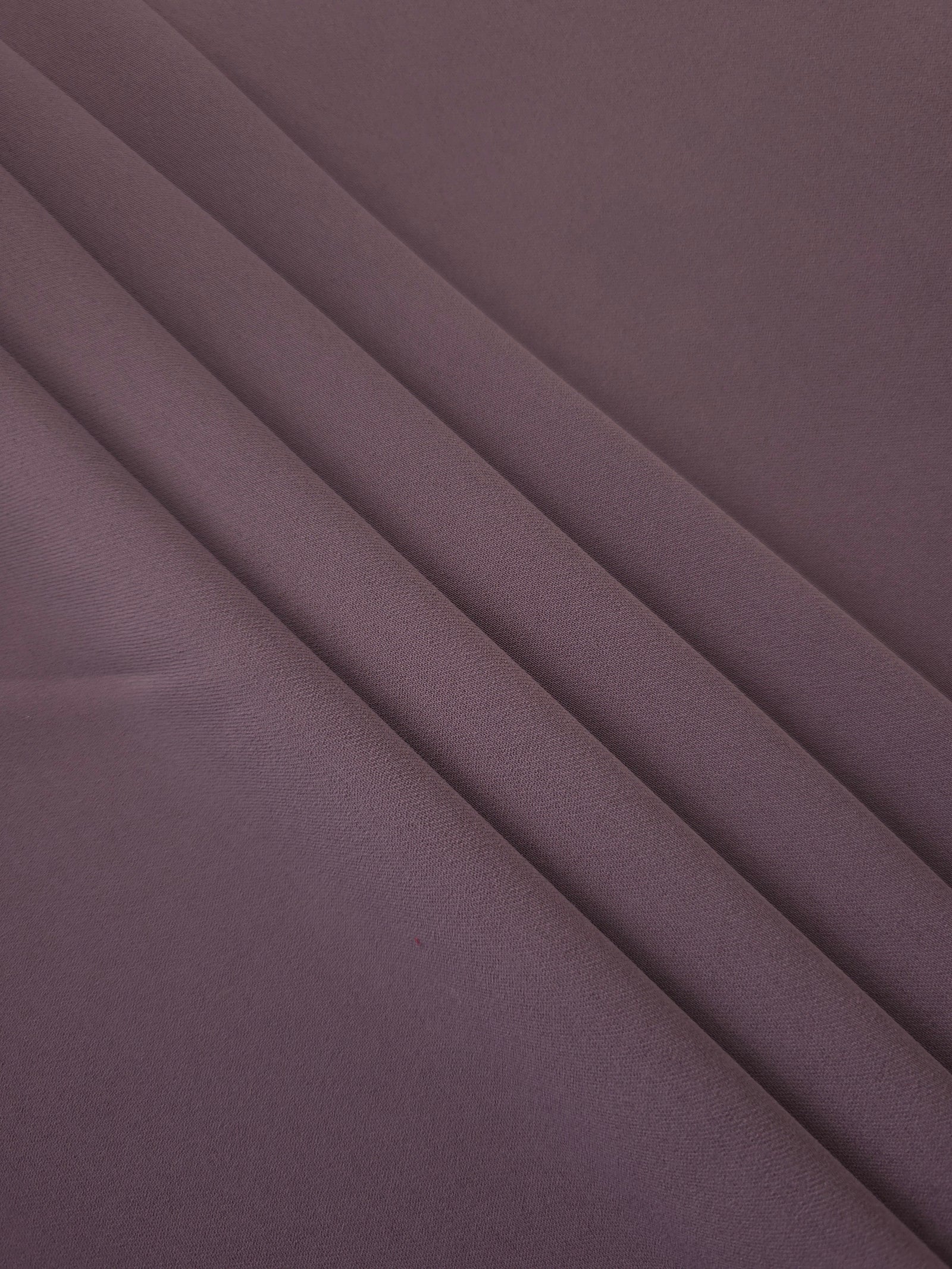Layered folds of Mauve Taupe 100% mechanical polyester crepe showing body and gentle construction stretch