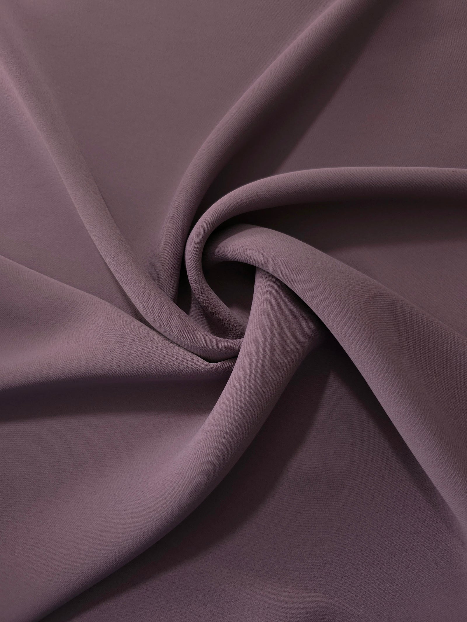 Mauve Taupe opaque polyester crepe in a spiral drape, showing flowing form for skirts and modest garments