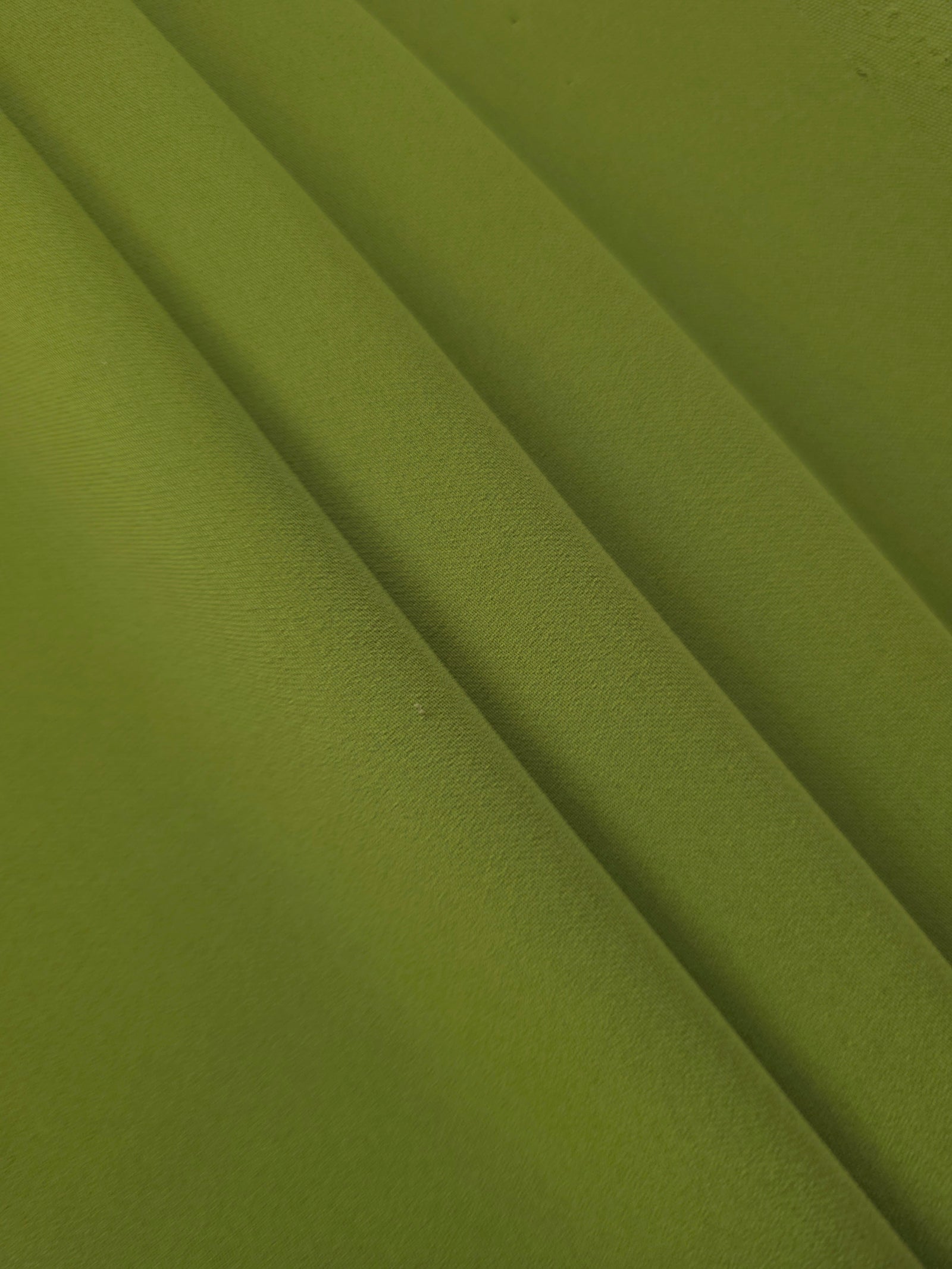 Layered folds of Moss Green 100% mechanical polyester crepe showing body and gentle construction stretch