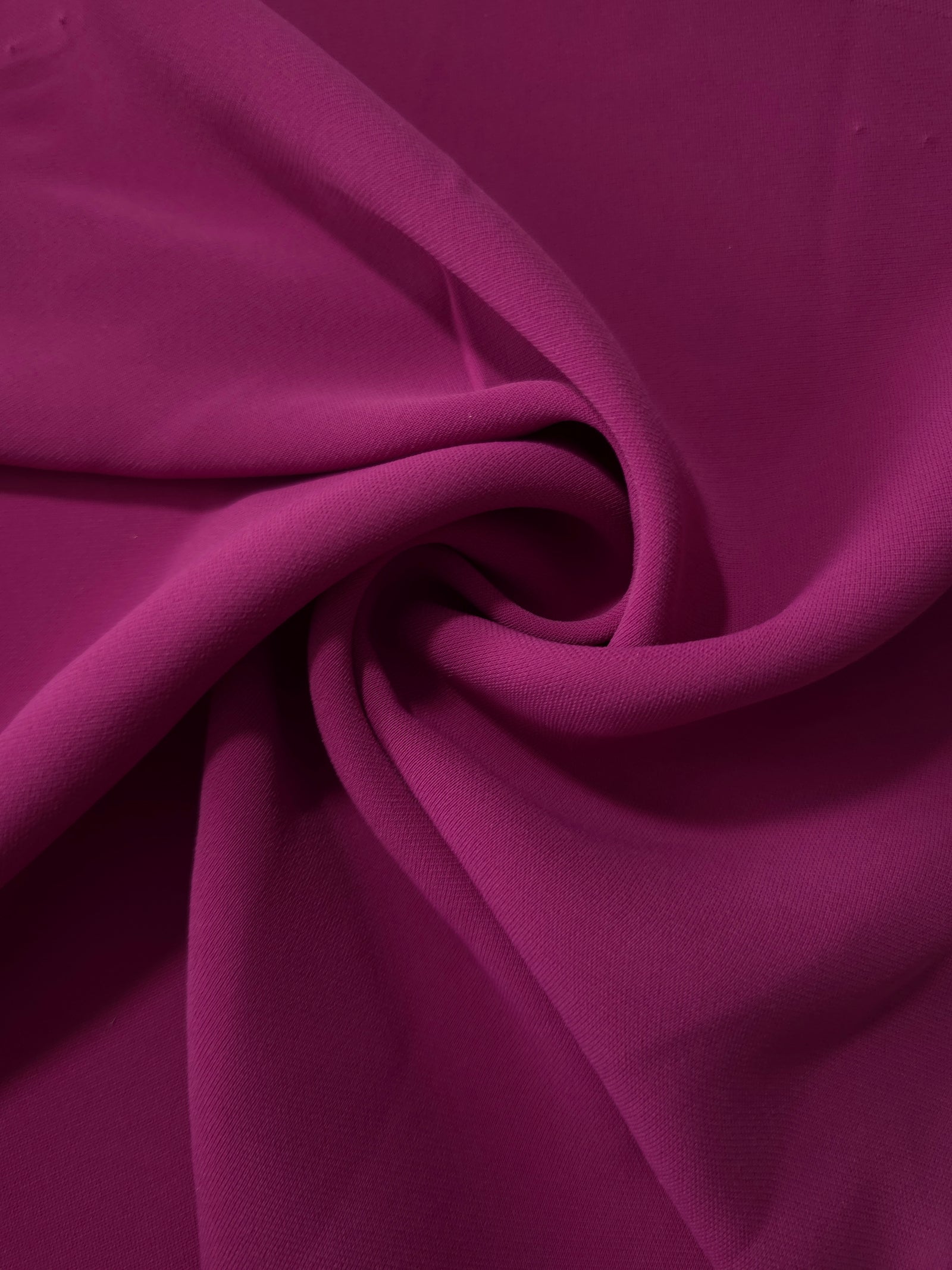 Mulberry Purple polyester crepe arranged in a flowing swirl, showing drape used for abayas and modest fashion