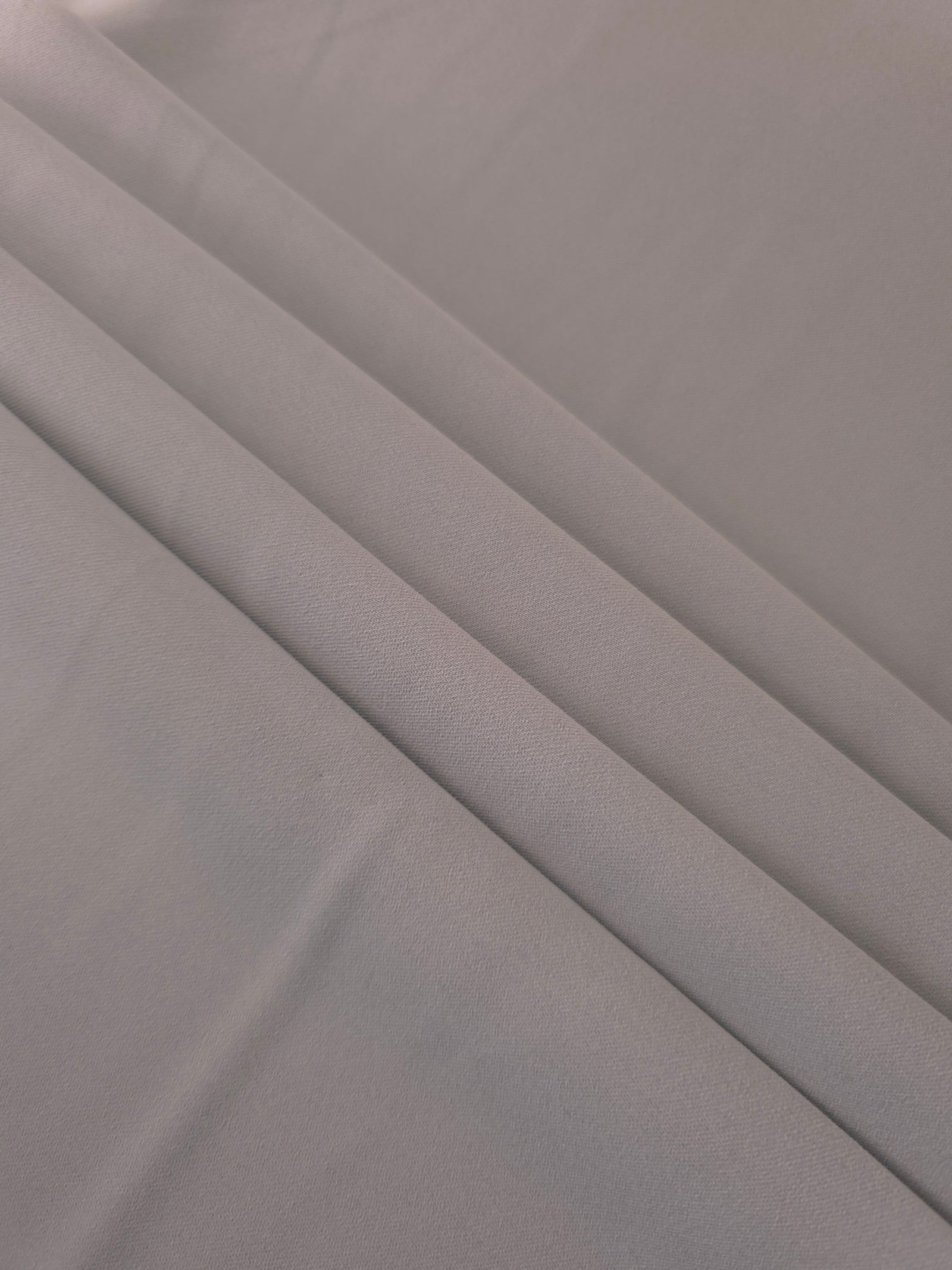 Layered Mushroom Greige mechanical polyester crepe showing soft structure and slight mechanical stretch for tailoring