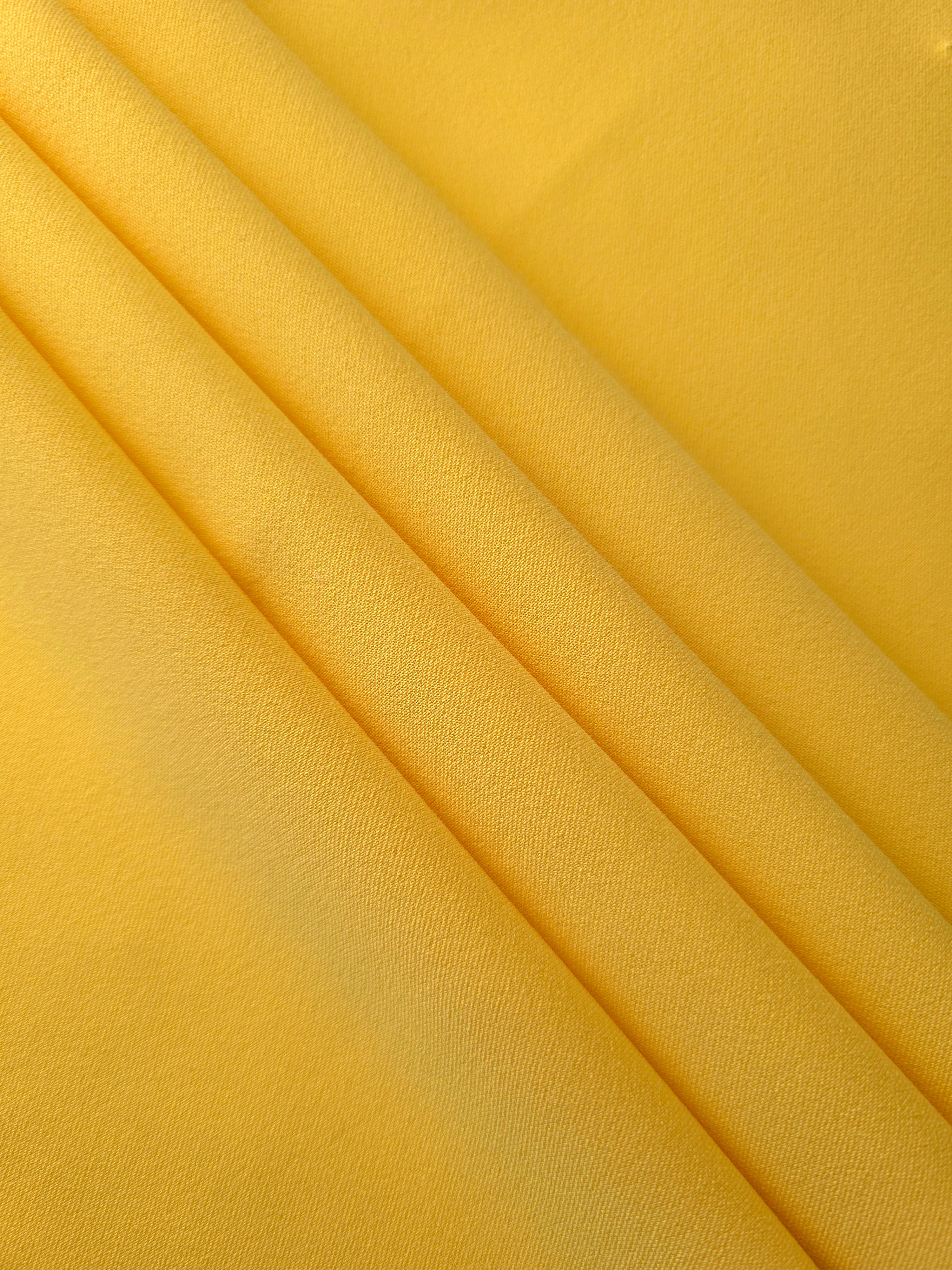 Layered Mustard Yellow mechanical polyester crepe showing soft structure and slight mechanical stretch for tailoring