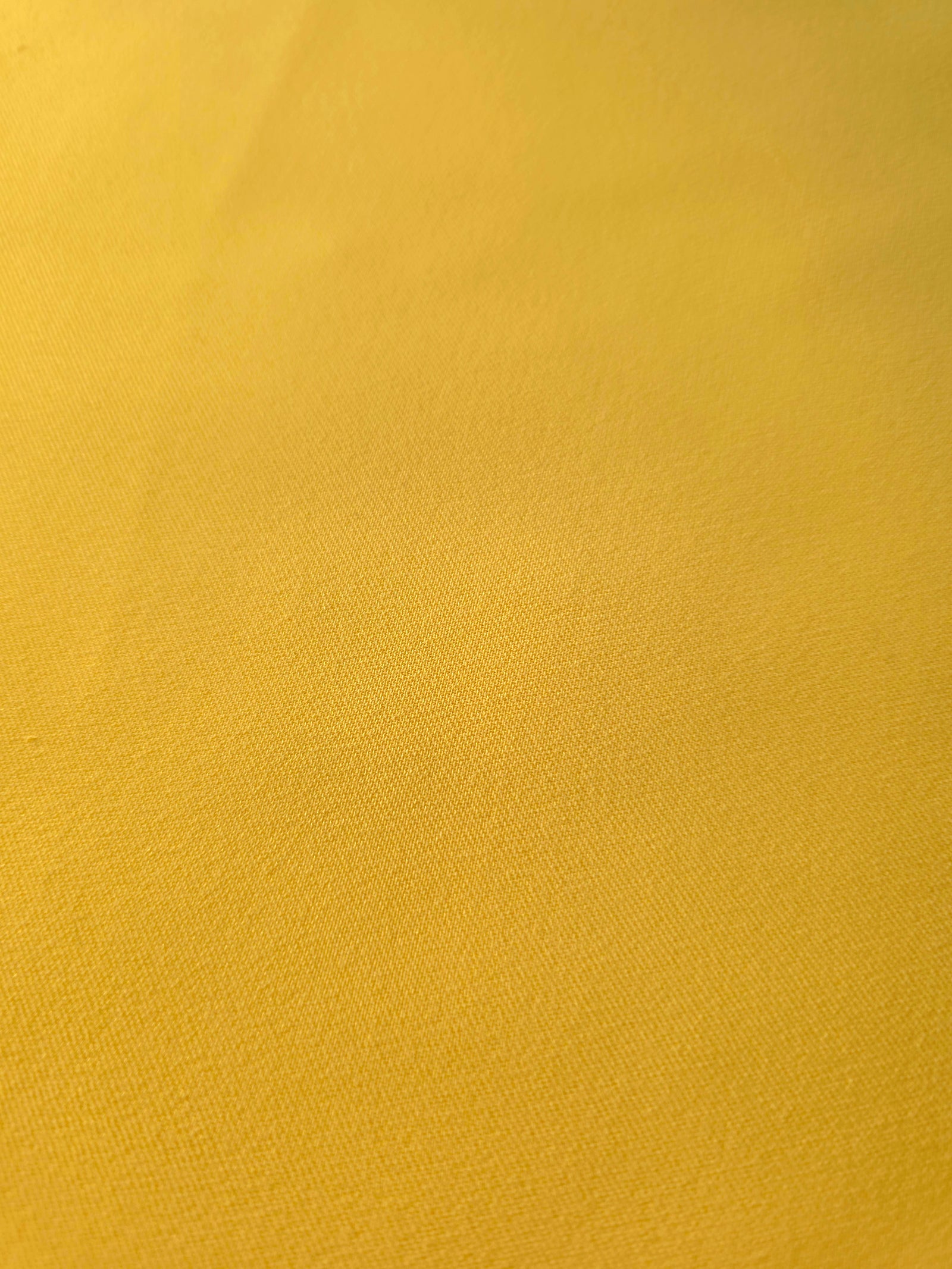 Close-up of Mustard Yellow 100% mechanical polyester crepe showing fine woven texture and a silky-soft hand feel