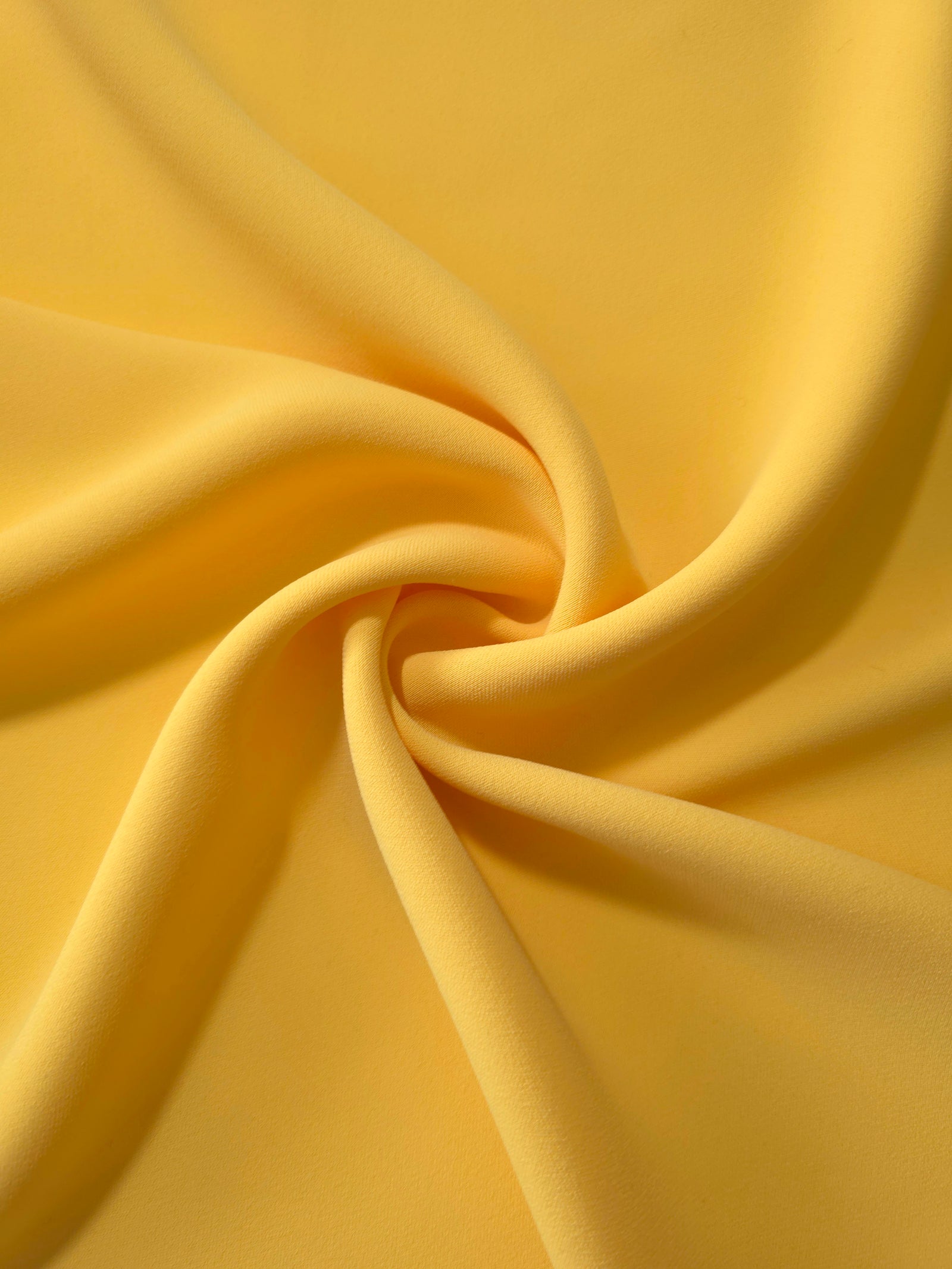 Mustard Yellow polyester crepe arranged in a flowing swirl, showing drape used for abayas and modest fashion