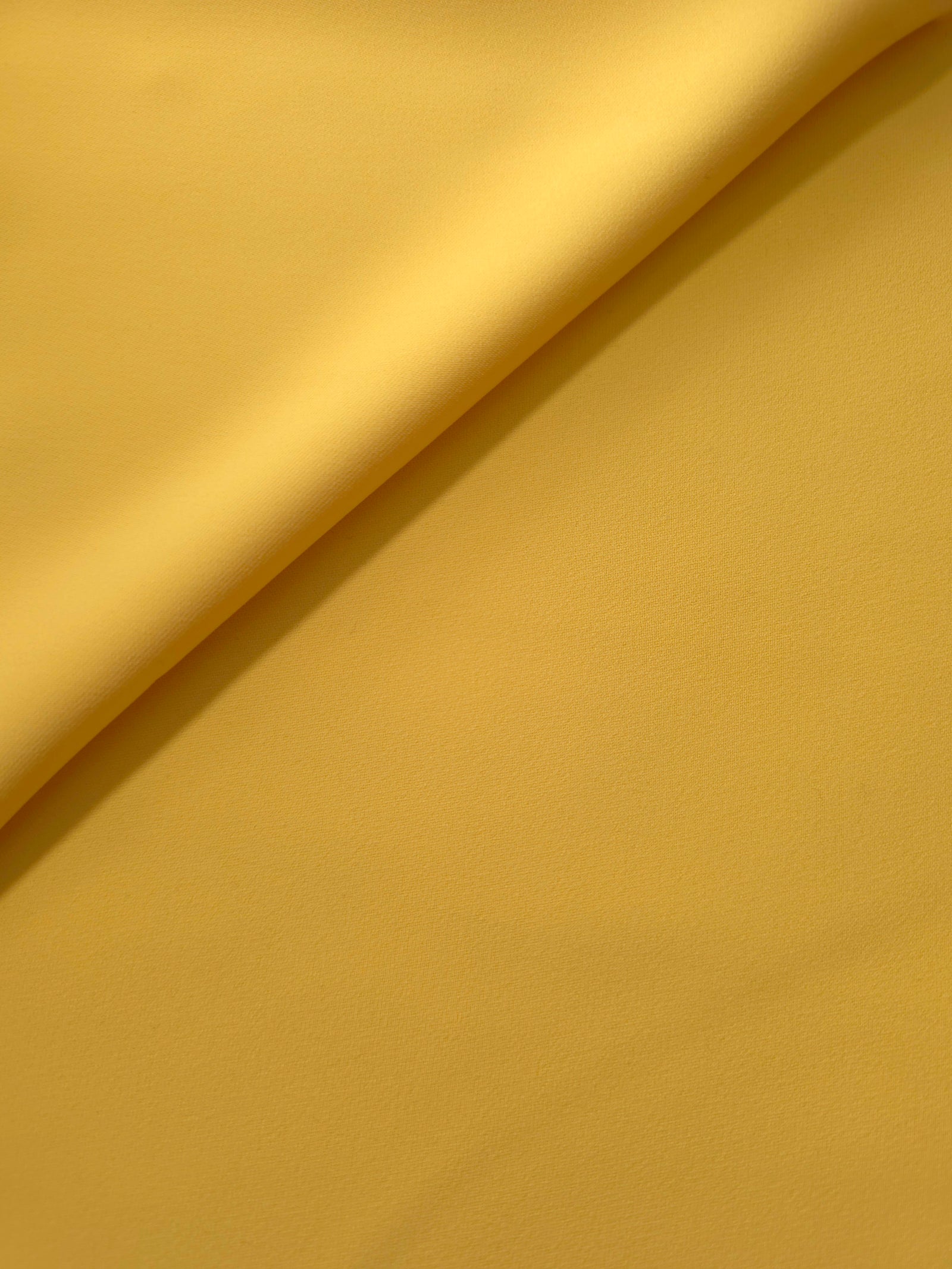 Mustard Yellow Korean polyester crepe in a soft fold, showing fluid drape for blouses and flowing dresses