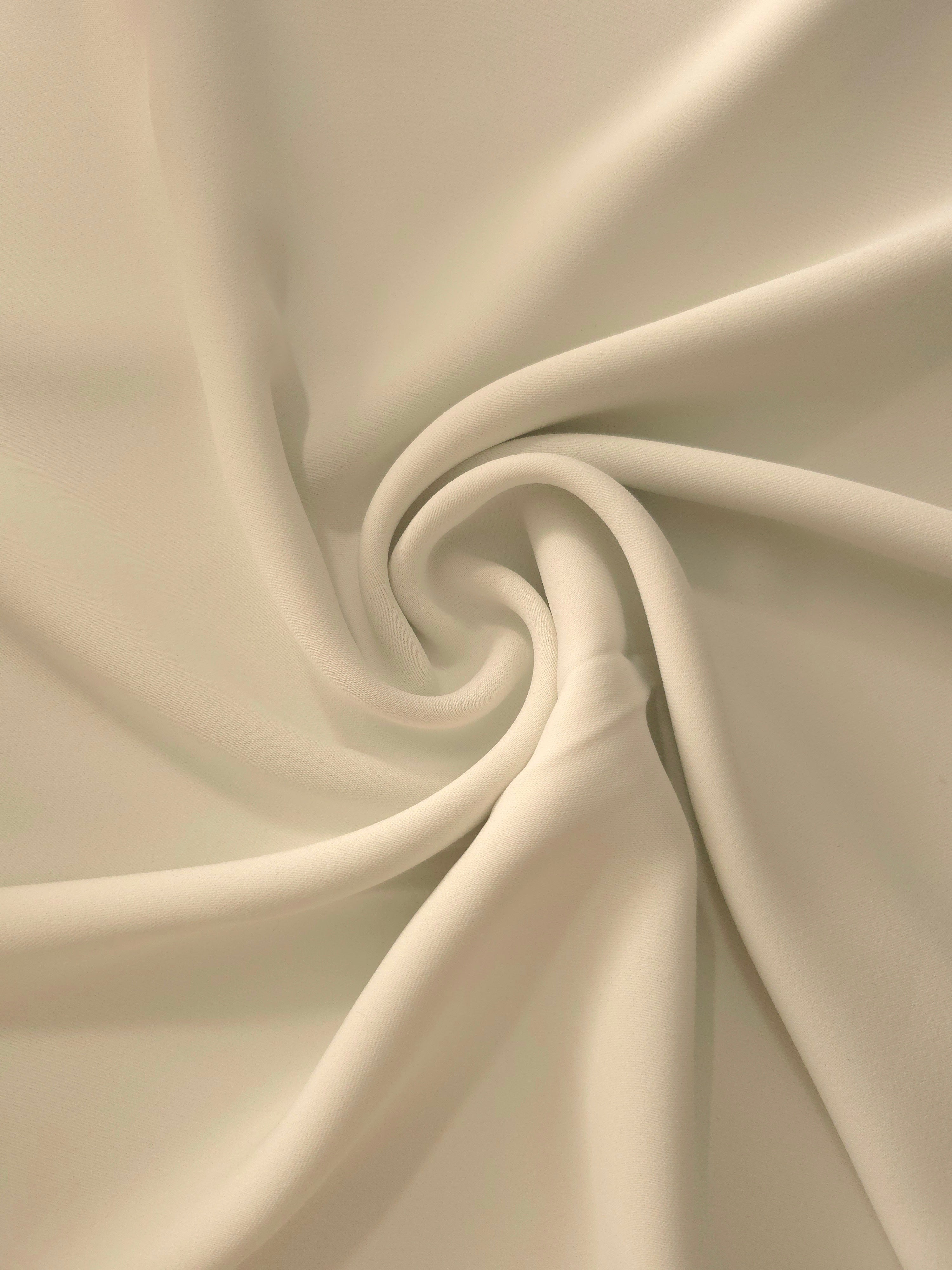 Oatmeal Beige Italian-style polyester crepe in a circular swirl, highlighting supple drape for garment making