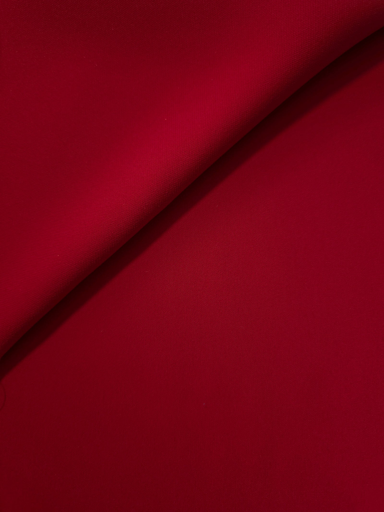 Soft fold of Oxblood Red opaque polyester crepe showing fluid dressmaking drape for dresses and skirts
