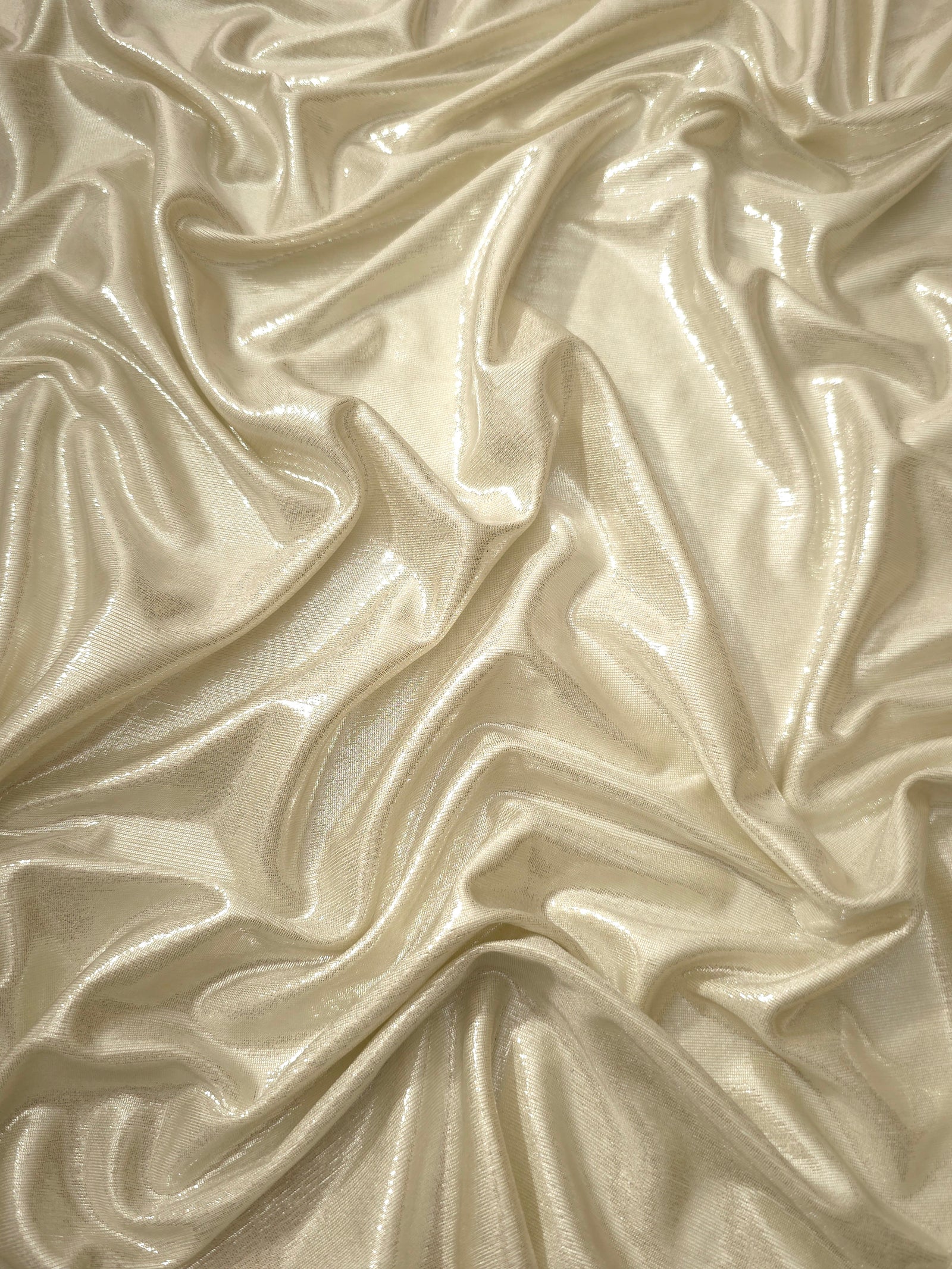 Flowing folds of Pale Butter Cream metallic foiled spandex, showing shimmer and drape for dancewear, party dresses and performance fashion
