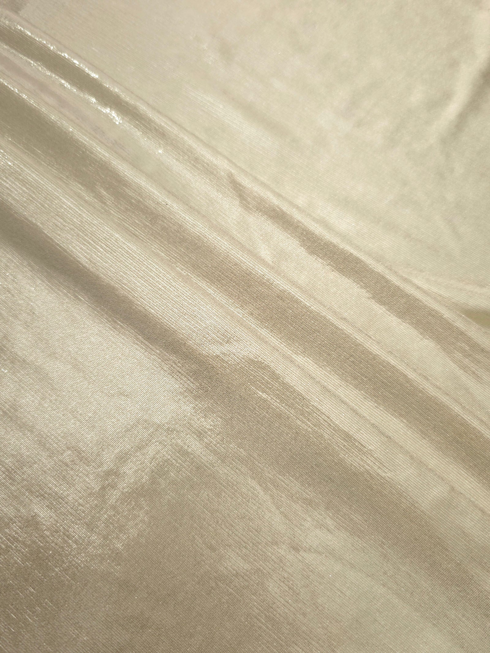 Layered folds of Pale Butter Cream foiled stretch fabric showing shimmer, body and movement for performance outfits and statement garments