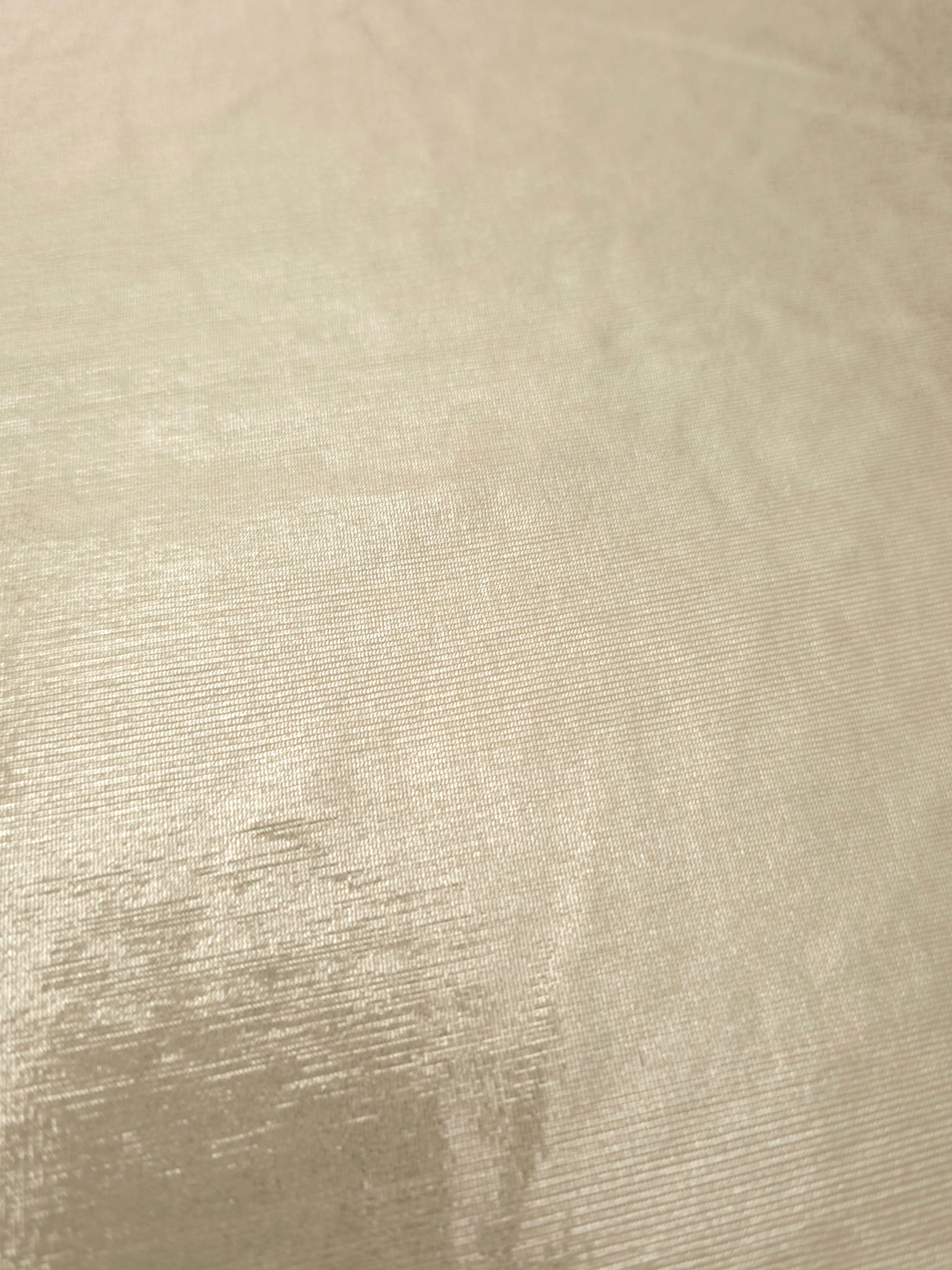 Detailed close-up of Pale Butter Cream foiled spandex fabric showing its luminous metallic surface and fine reflective texture