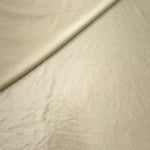 Pale Butter Cream foiled stretch fabric in a gentle fold, showing metallic shimmer and flexibility for partywear and performance fashion