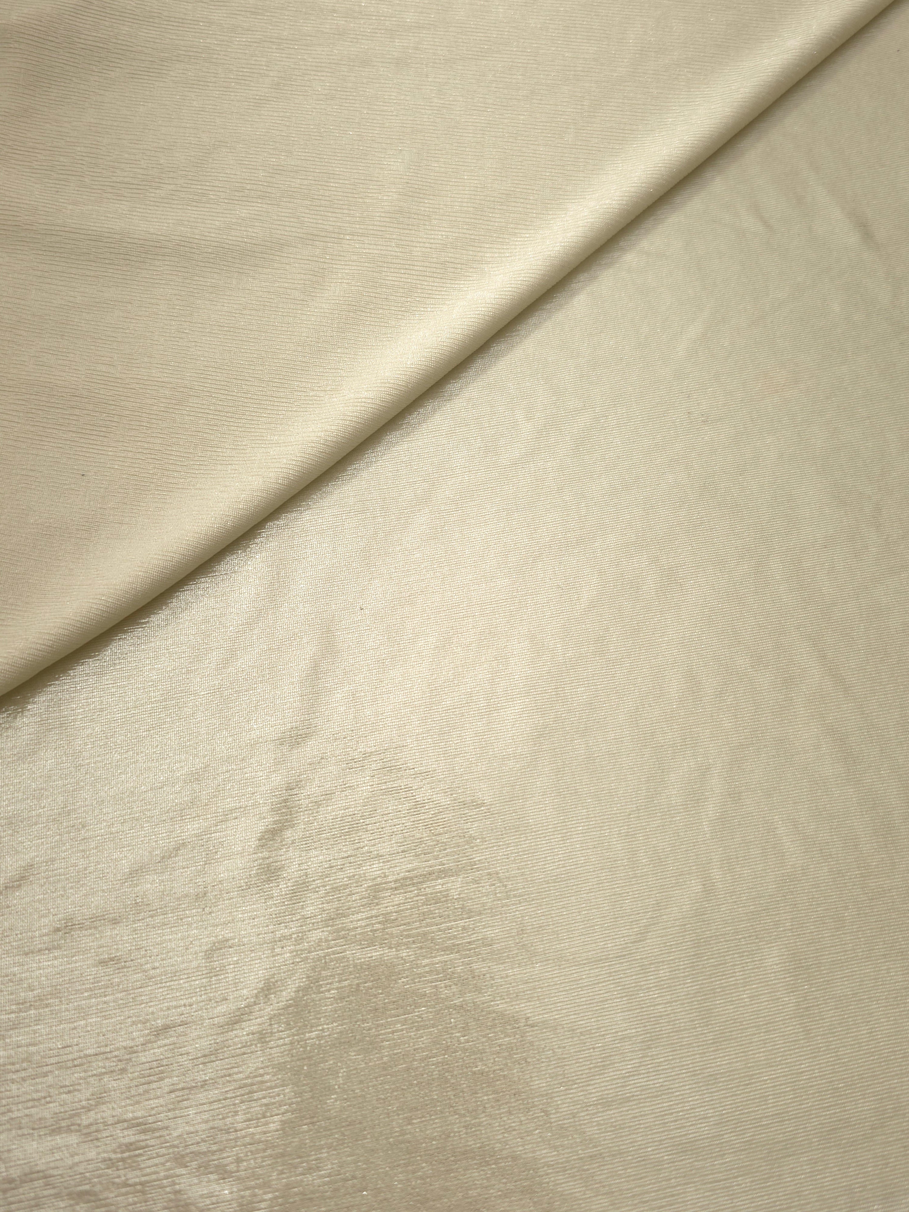 Pale Butter Cream foiled stretch fabric in a gentle fold, showing metallic shimmer and flexibility for partywear and performance fashion