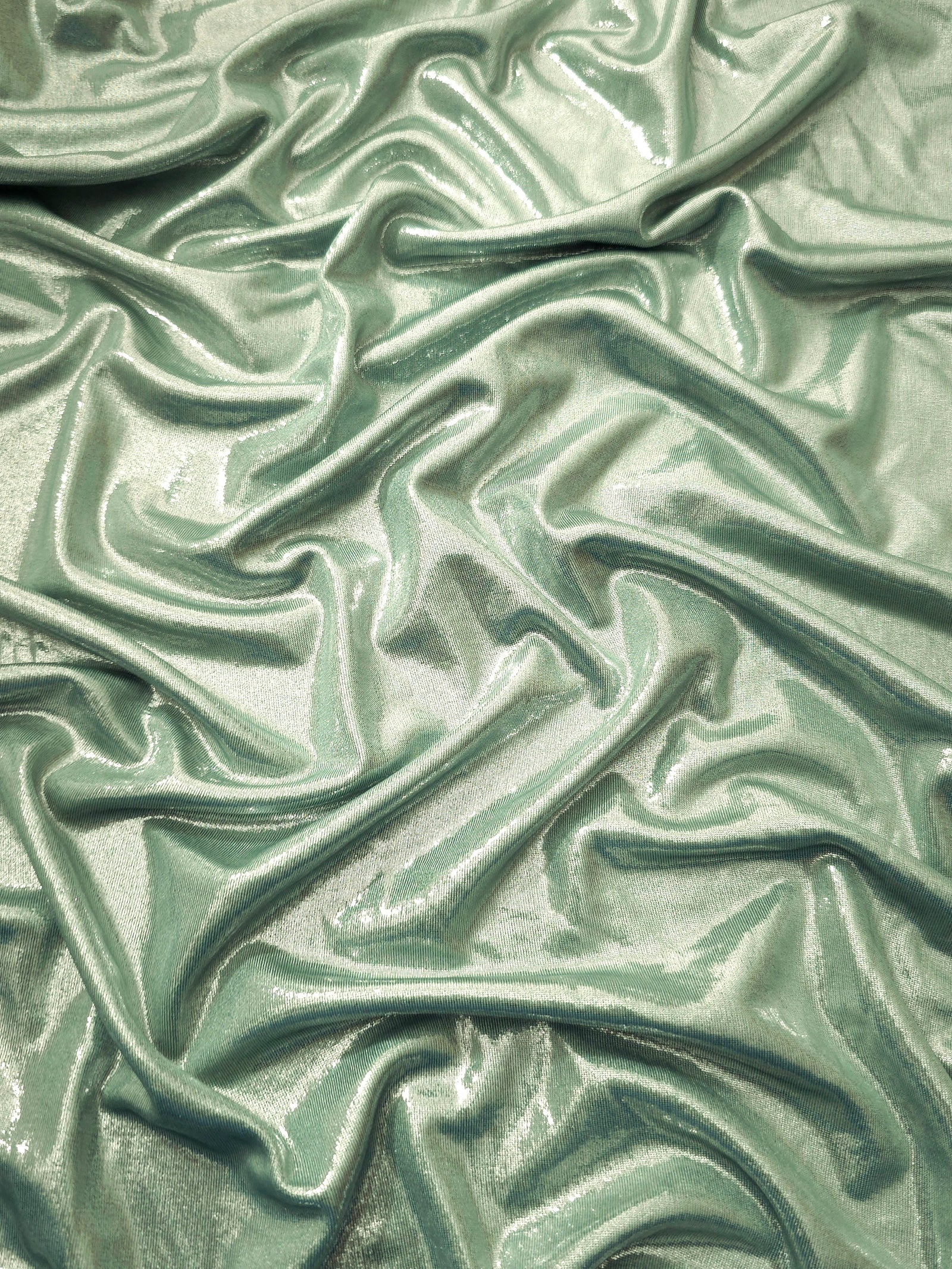 Pale Sage Green metallic stretch fabric arranged in elegant folds, showing reflective movement for occasionwear, costumes and fashion design