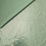 Pale Sage Green metallic stretch fabric in a soft fold, revealing reflective drape for dancewear, dresses and statement apparel