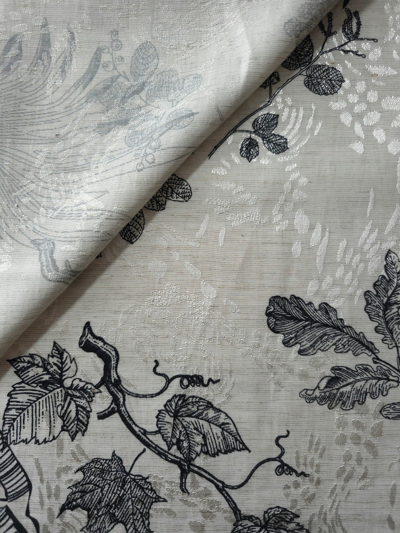 Black palm vine jacquard fabric close-up detail with woven leaf pattern and linen-look texture.
