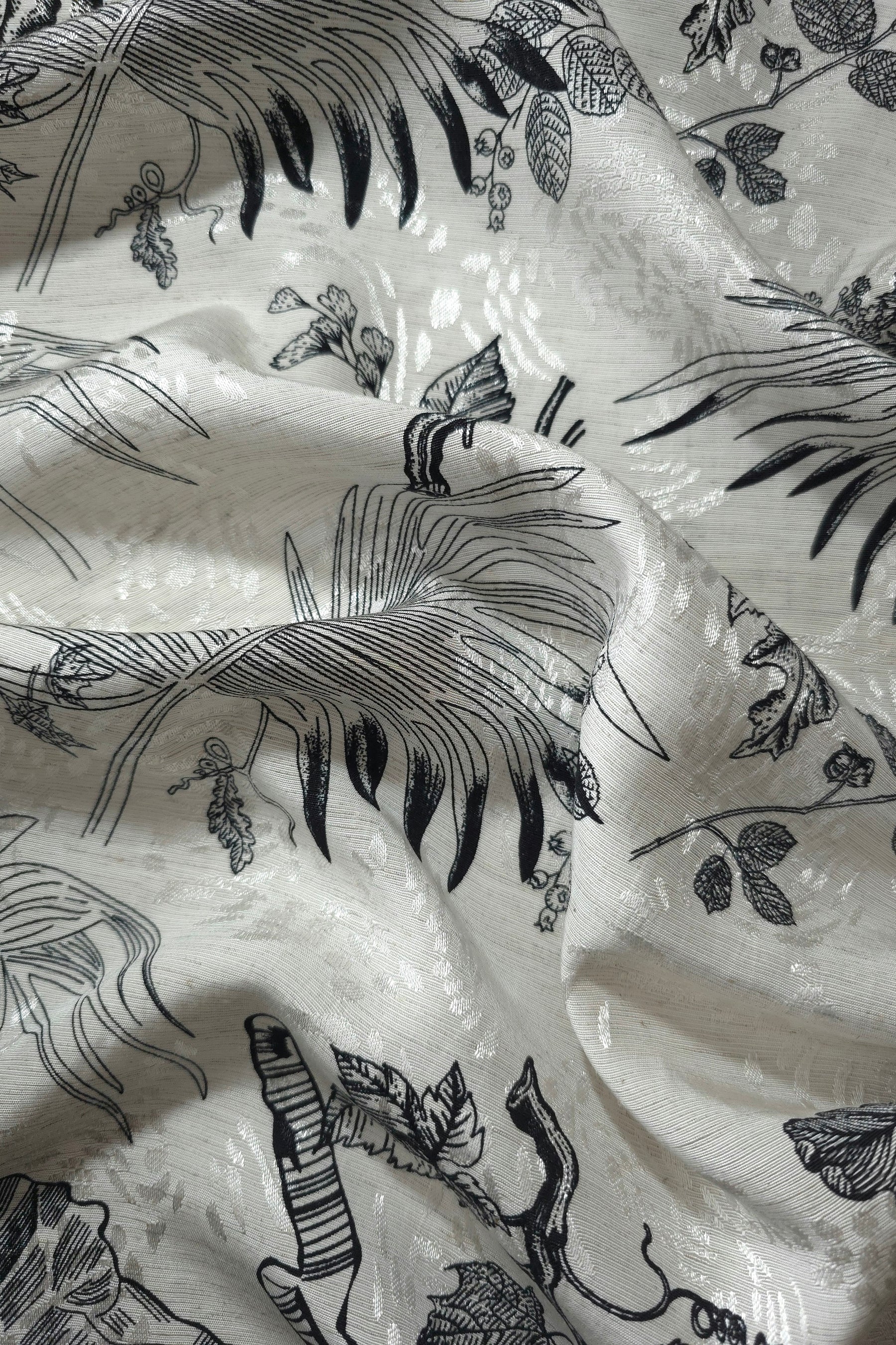 Black palm vine linen-look jacquard fabric draped to show soft structure and tonal botanical design.