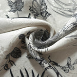 Black palm vine linen-look jacquard fabric folded view showing matte texture and woven pattern.