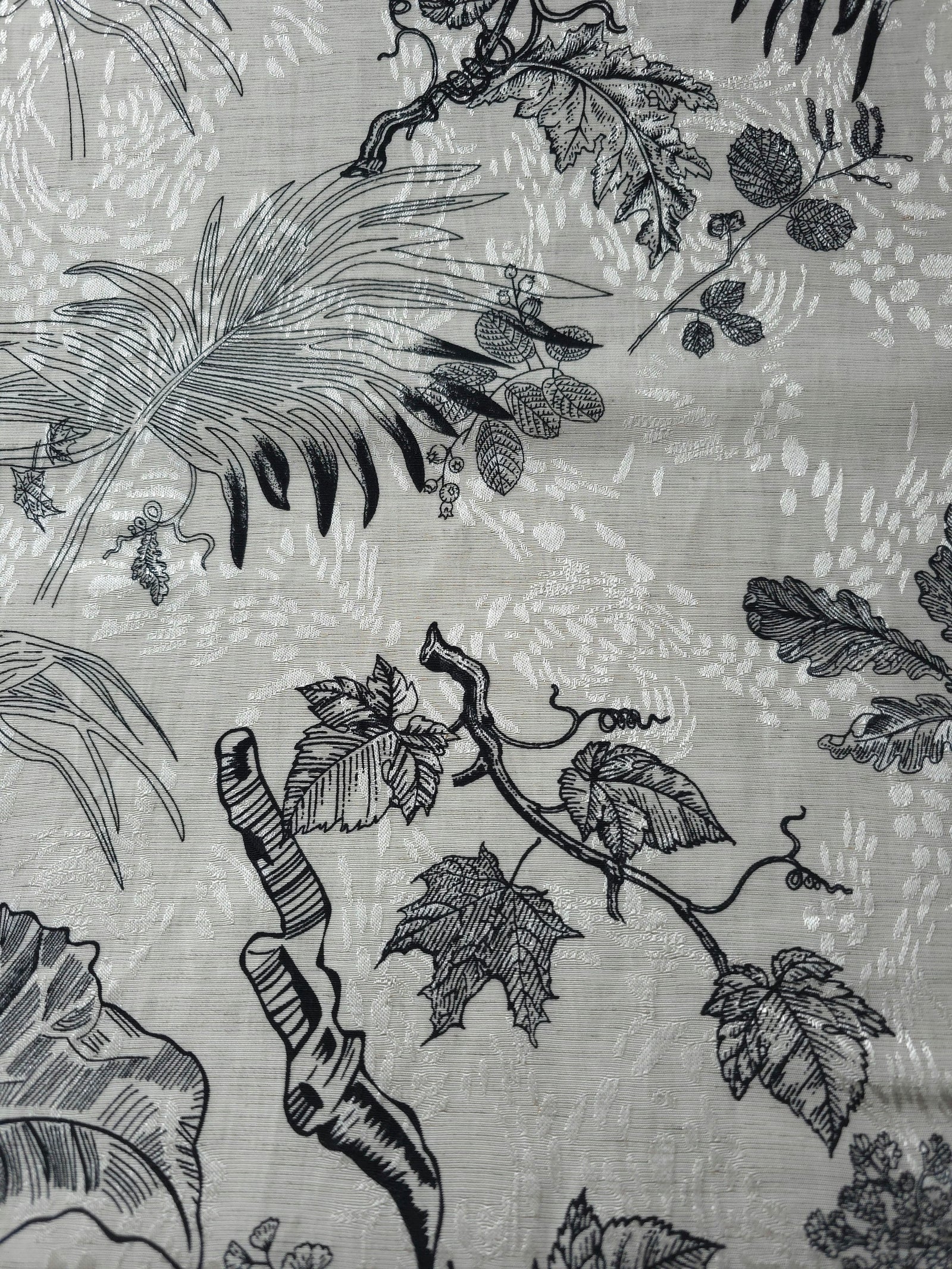 Texture view of black palm vine linen-look jacquard fabric with subtle woven botanical pattern.
