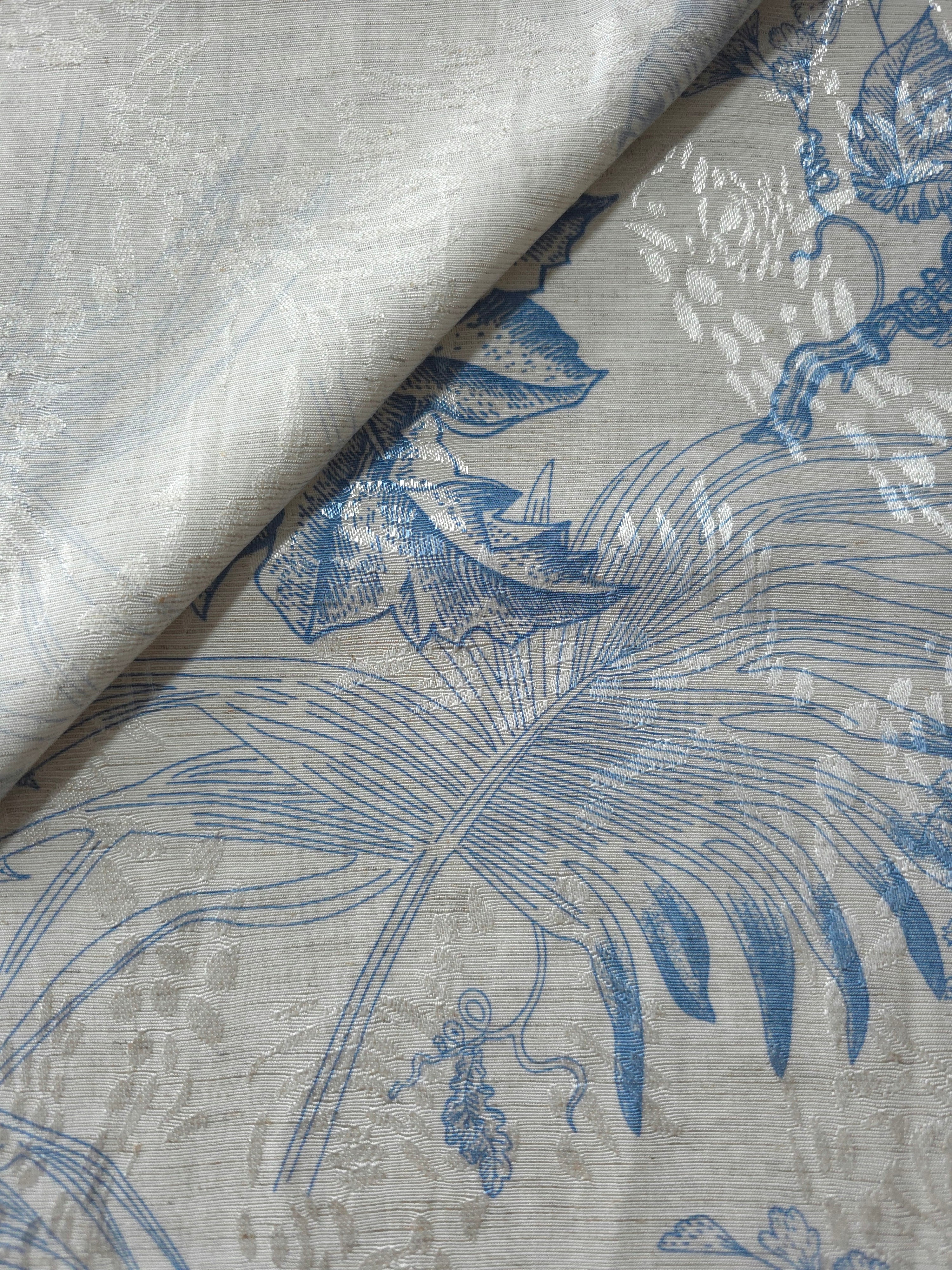 Blue palm vine jacquard fabric close-up detail with linen-look texture and tonal leaf motif.