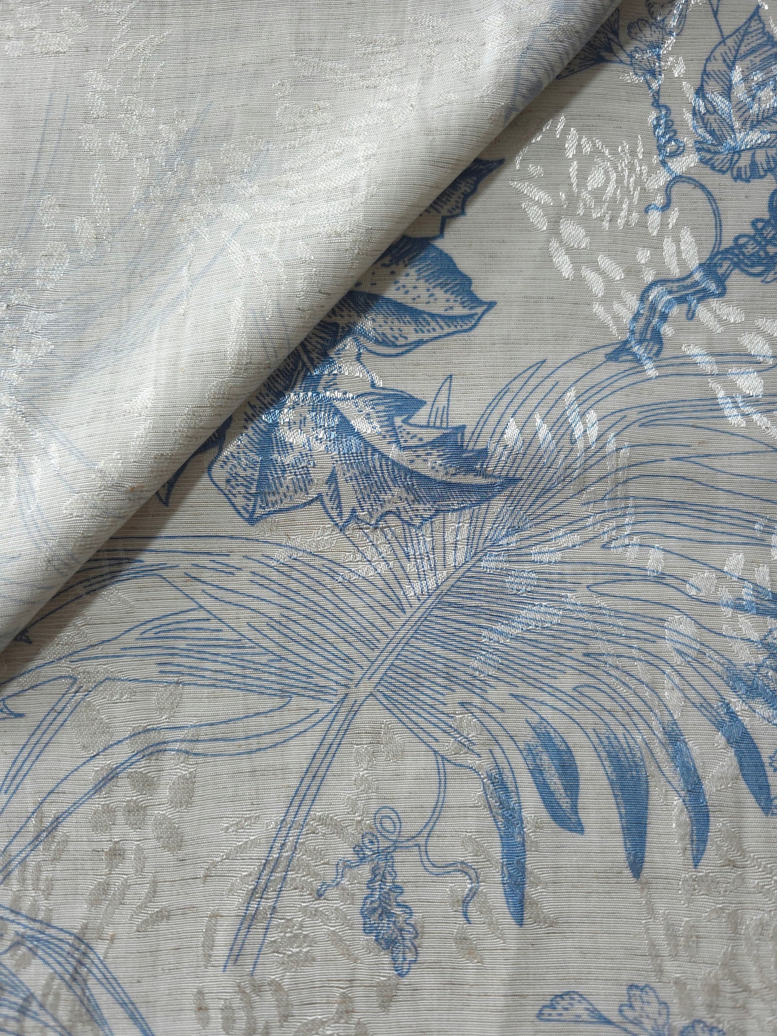 Blue palm vine jacquard fabric close-up detail with linen-look texture and tonal leaf motif.