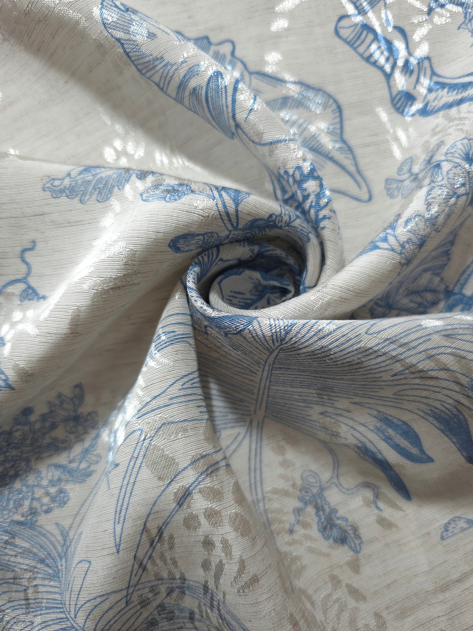 Blue palm vine linen-look jacquard fabric draped to show soft structure and woven botanical movement.