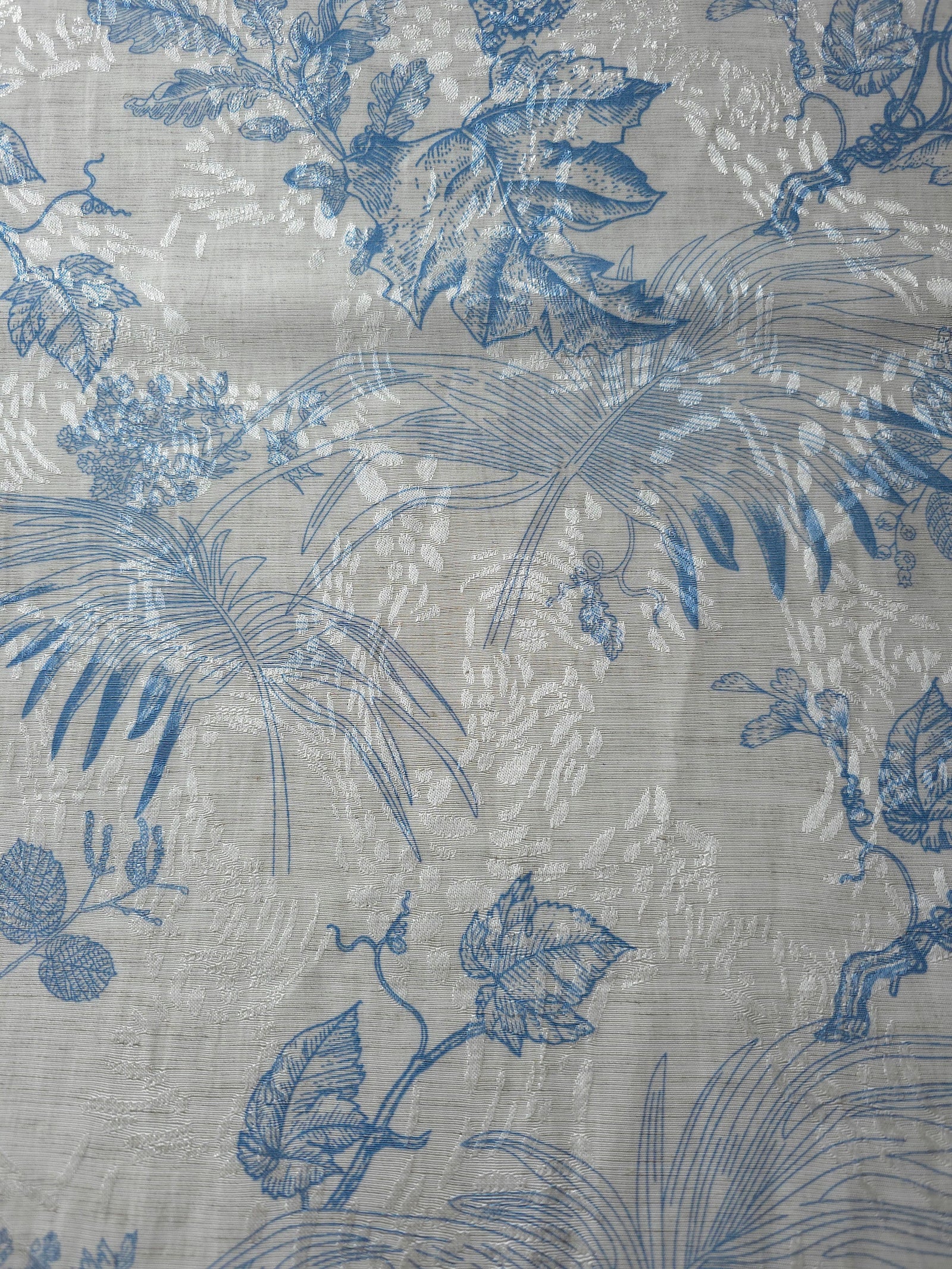 Blue palm vine linen-look jacquard fabric texture view with woven botanical pattern.