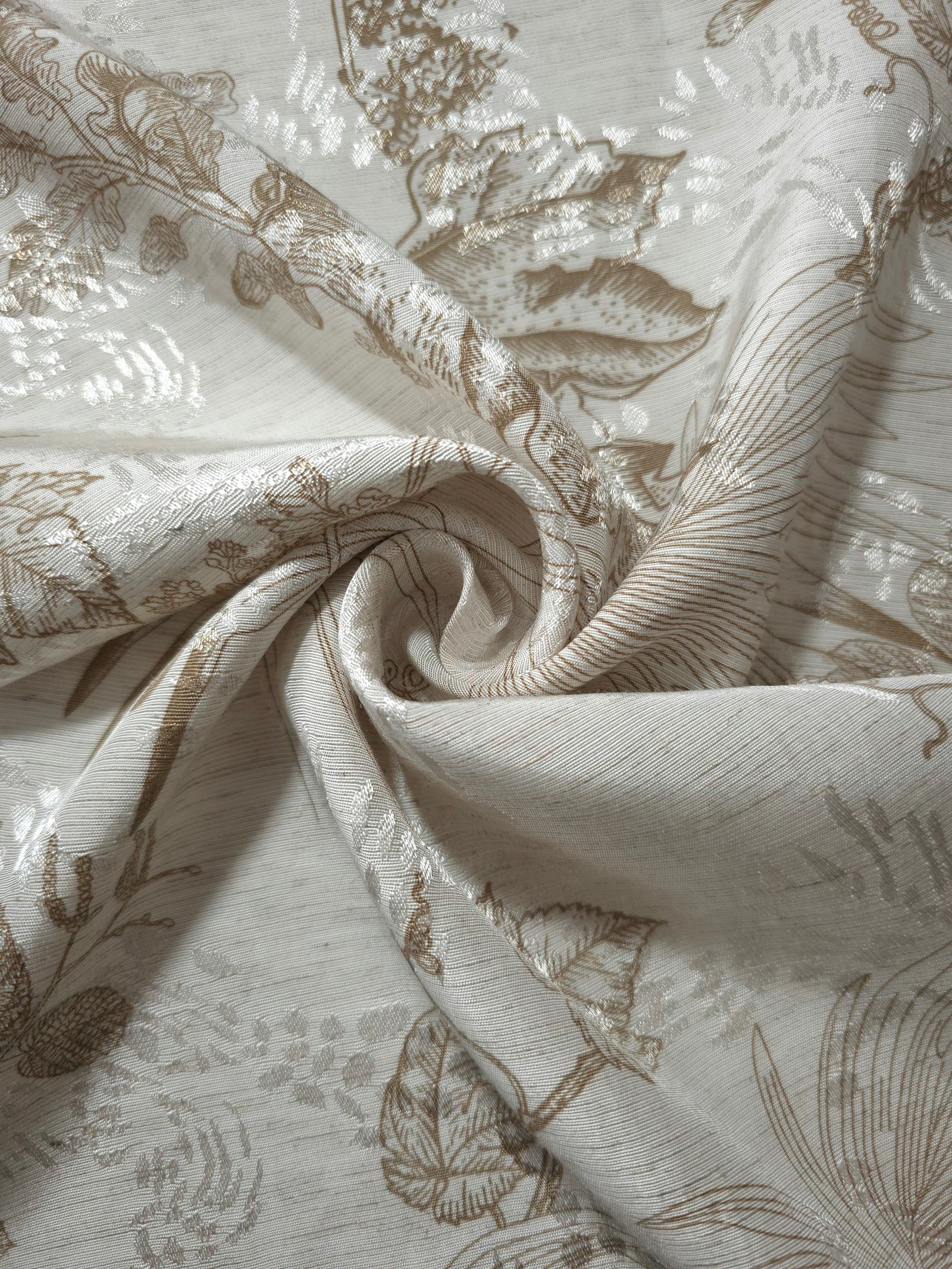 Brown palm vine linen-look jacquard fabric folded view showing apparel drape and woven leaf design.