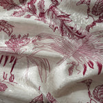 Deep red palm vine linen-look jacquard fabric draped to show soft structure and pattern depth.