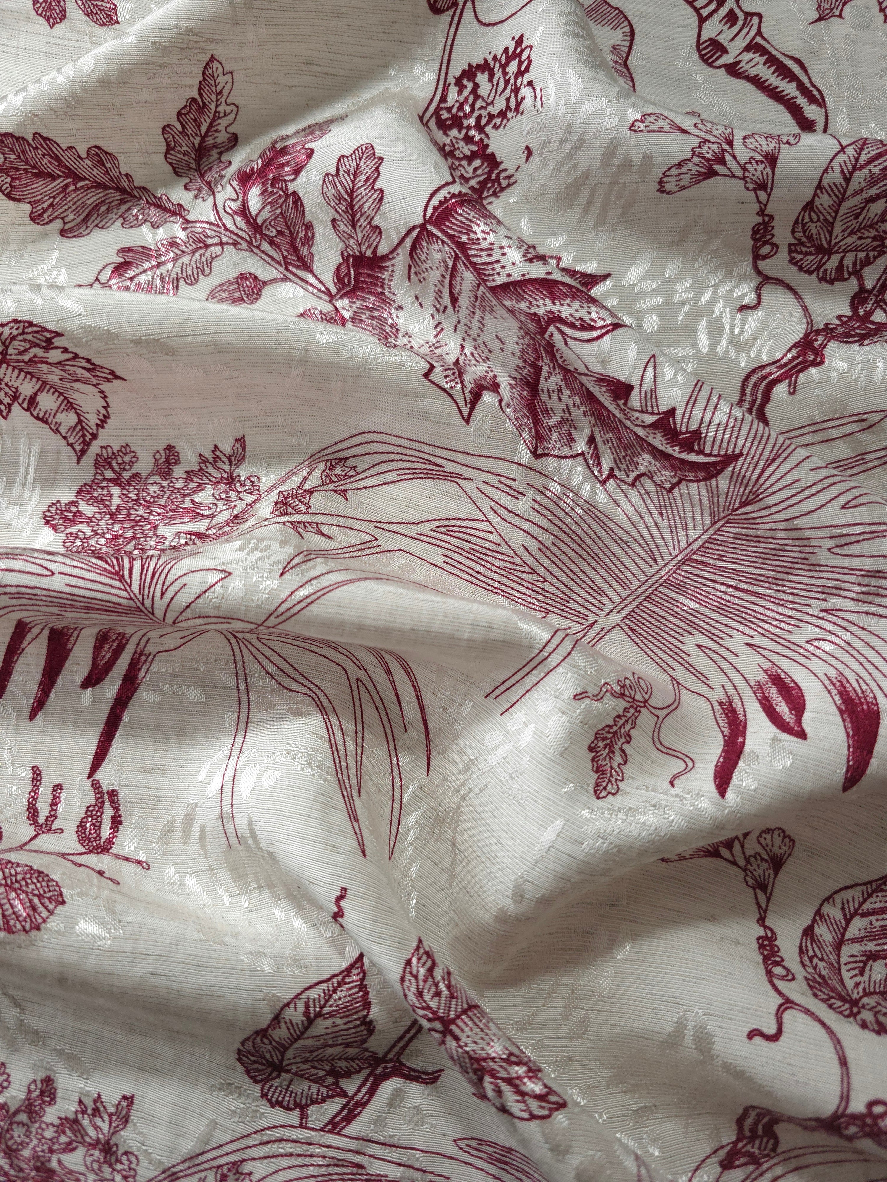 Deep red palm vine linen-look jacquard fabric draped to show soft structure and pattern depth.