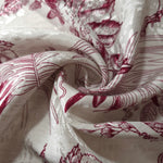 Deep red palm vine linen-look jacquard fabric folded view showing apparel drape and texture.