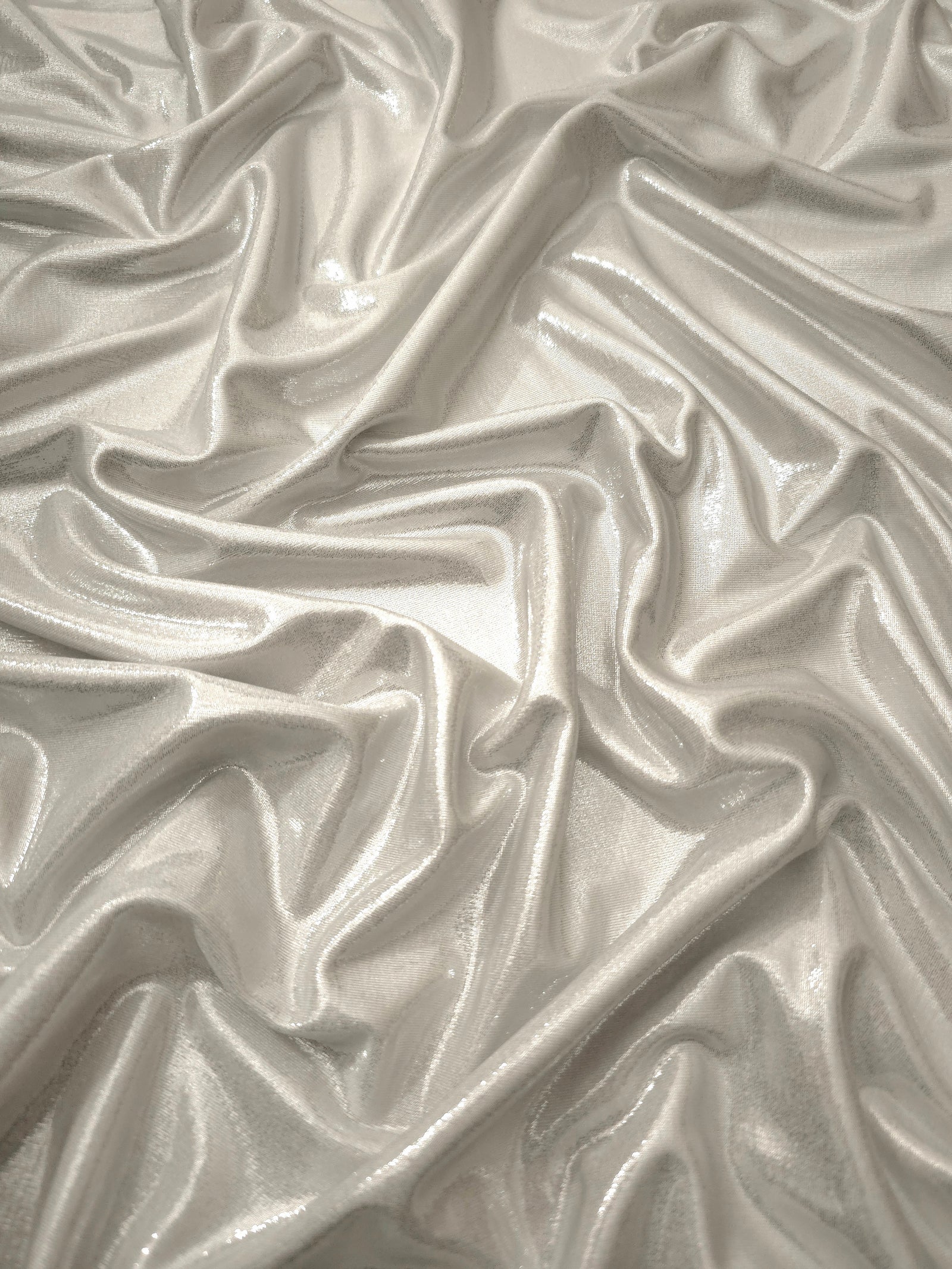 Flowing folds of Pearl Ivory metallic foiled spandex, showing shimmer and drape for dancewear, party dresses and performance fashion