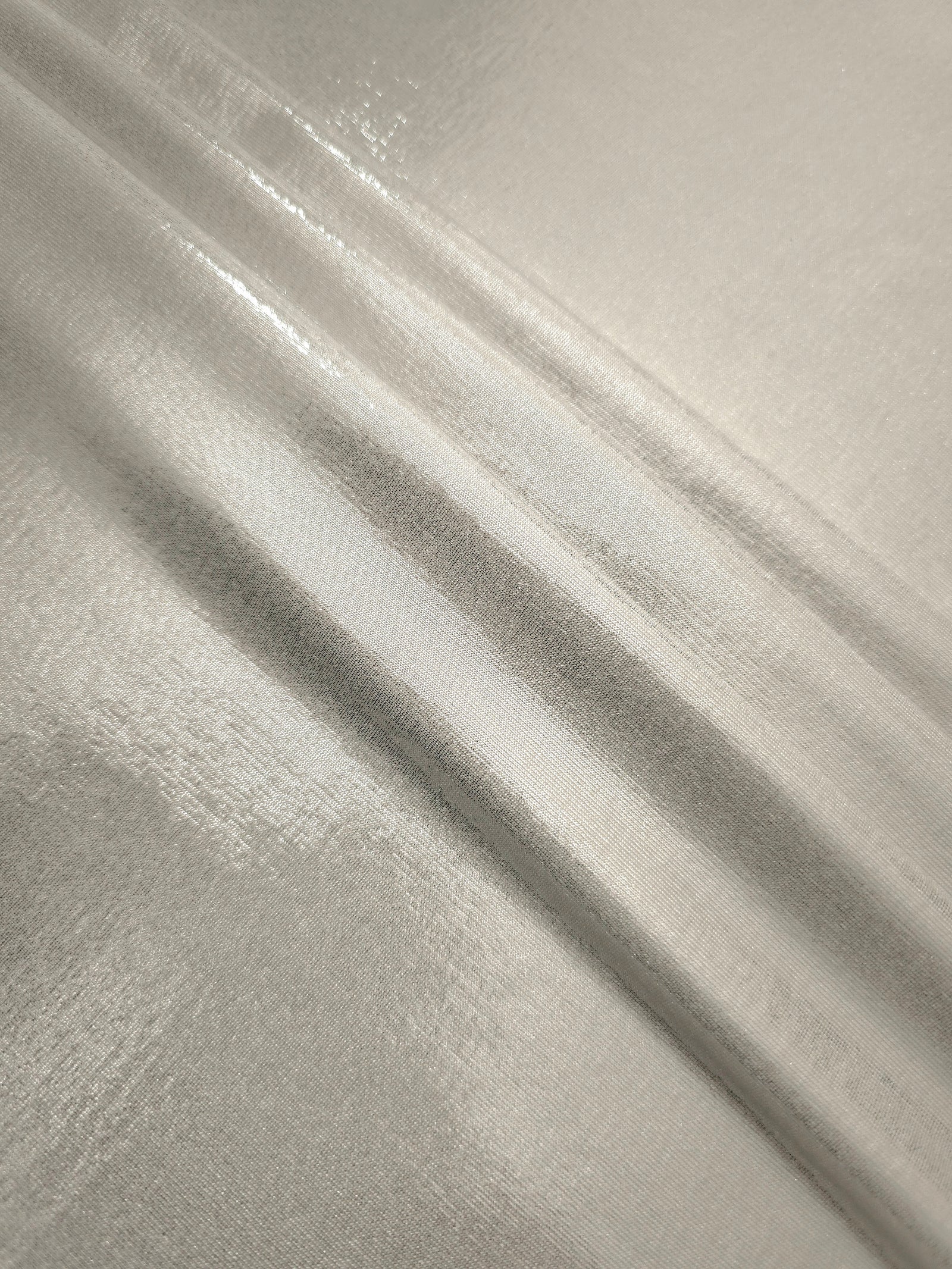 Layered folds of Pearl Ivory foiled stretch fabric showing shimmer, body and movement for performance outfits and statement garments